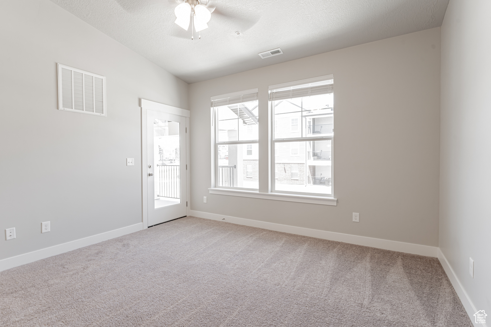 Empty room featuring carpet floors, ceiling fan, and plenty of natural light