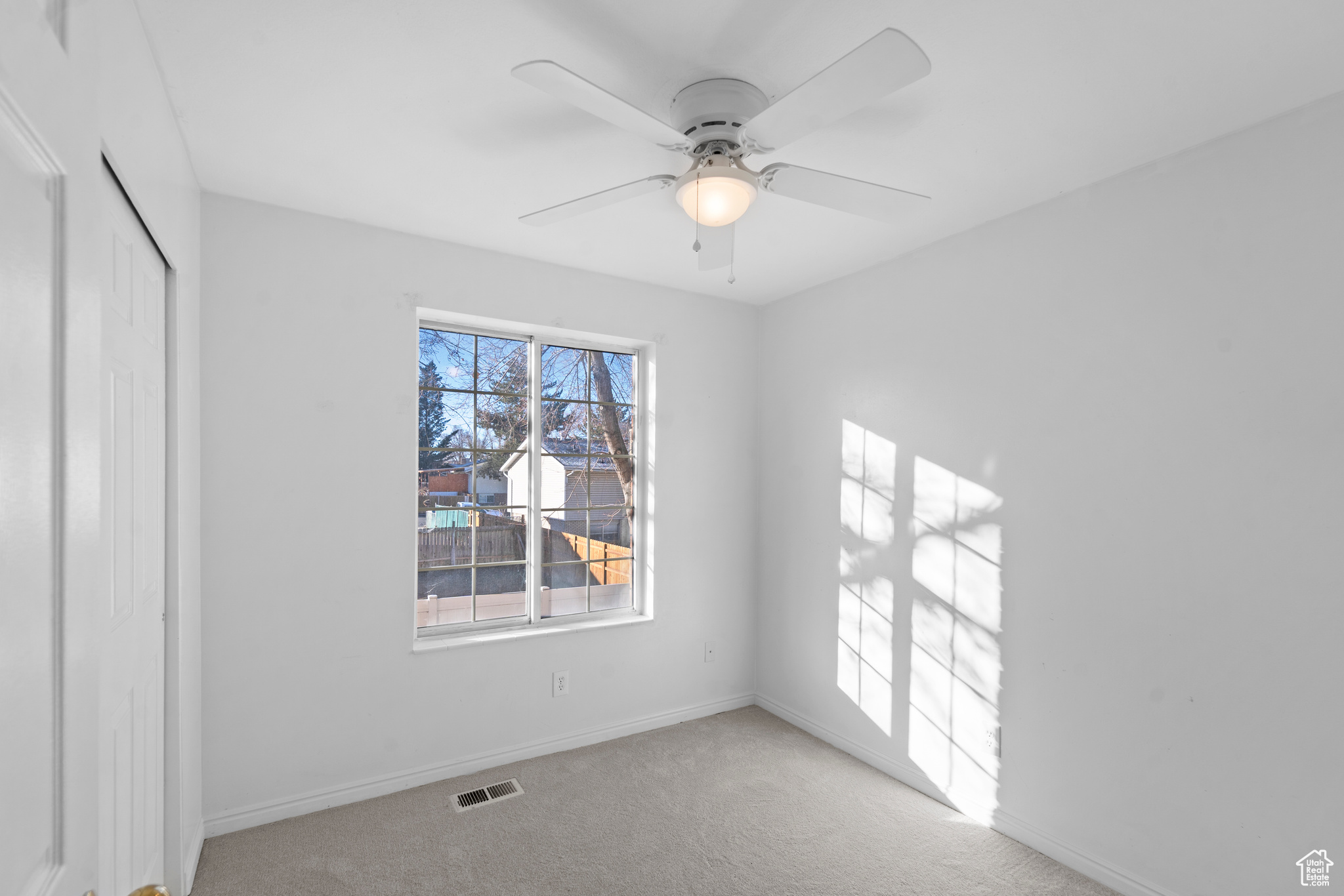 Second room featuring ceiling fan and light carpet