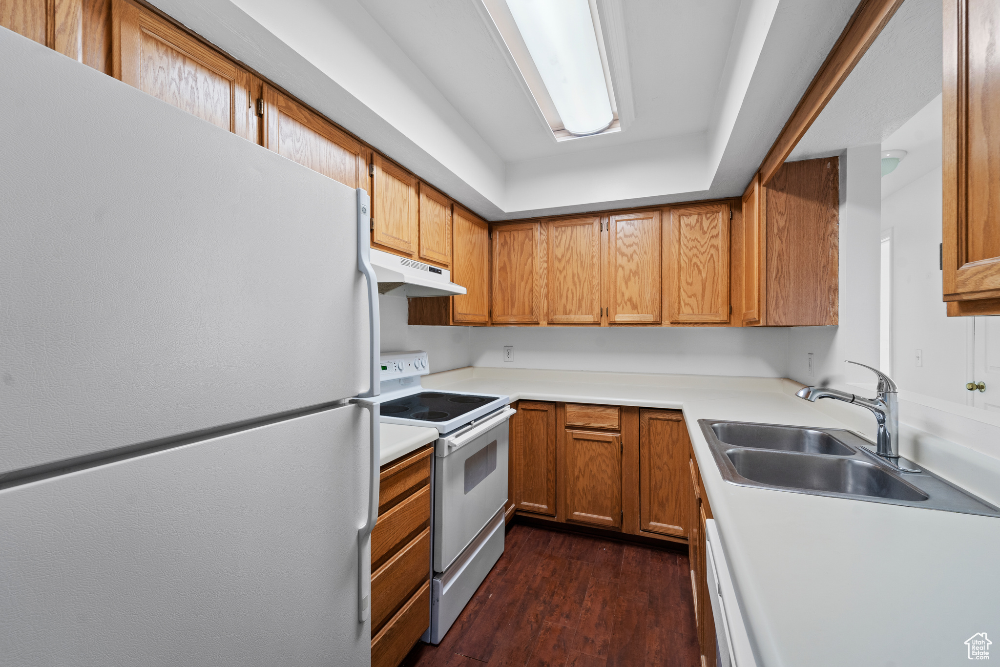 Kitchen with white appliances, dark hardwood-style laminate