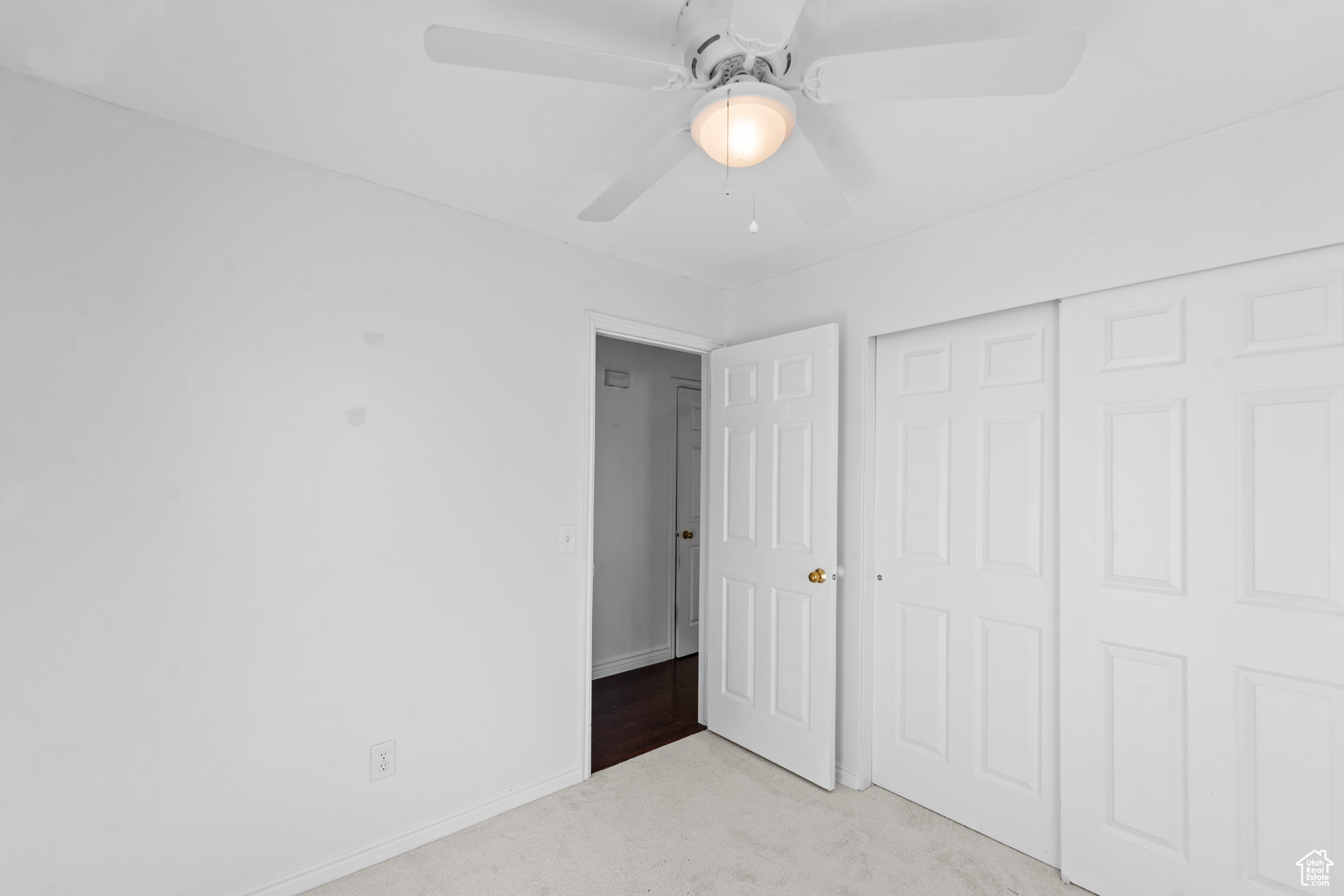 Second bedroom with light carpet, ceiling fan, and a closet