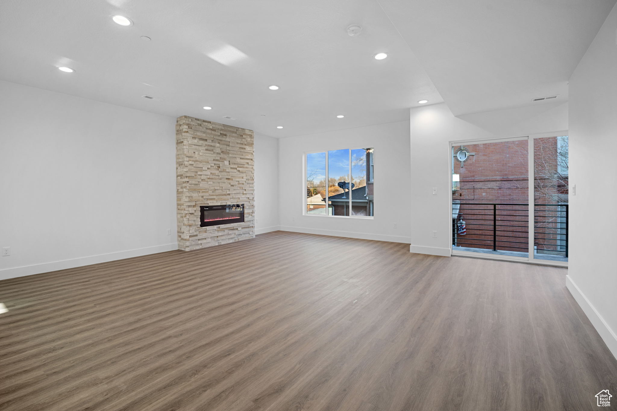 Unfurnished living room featuring hardwood / wood-style floors and a stone fireplace