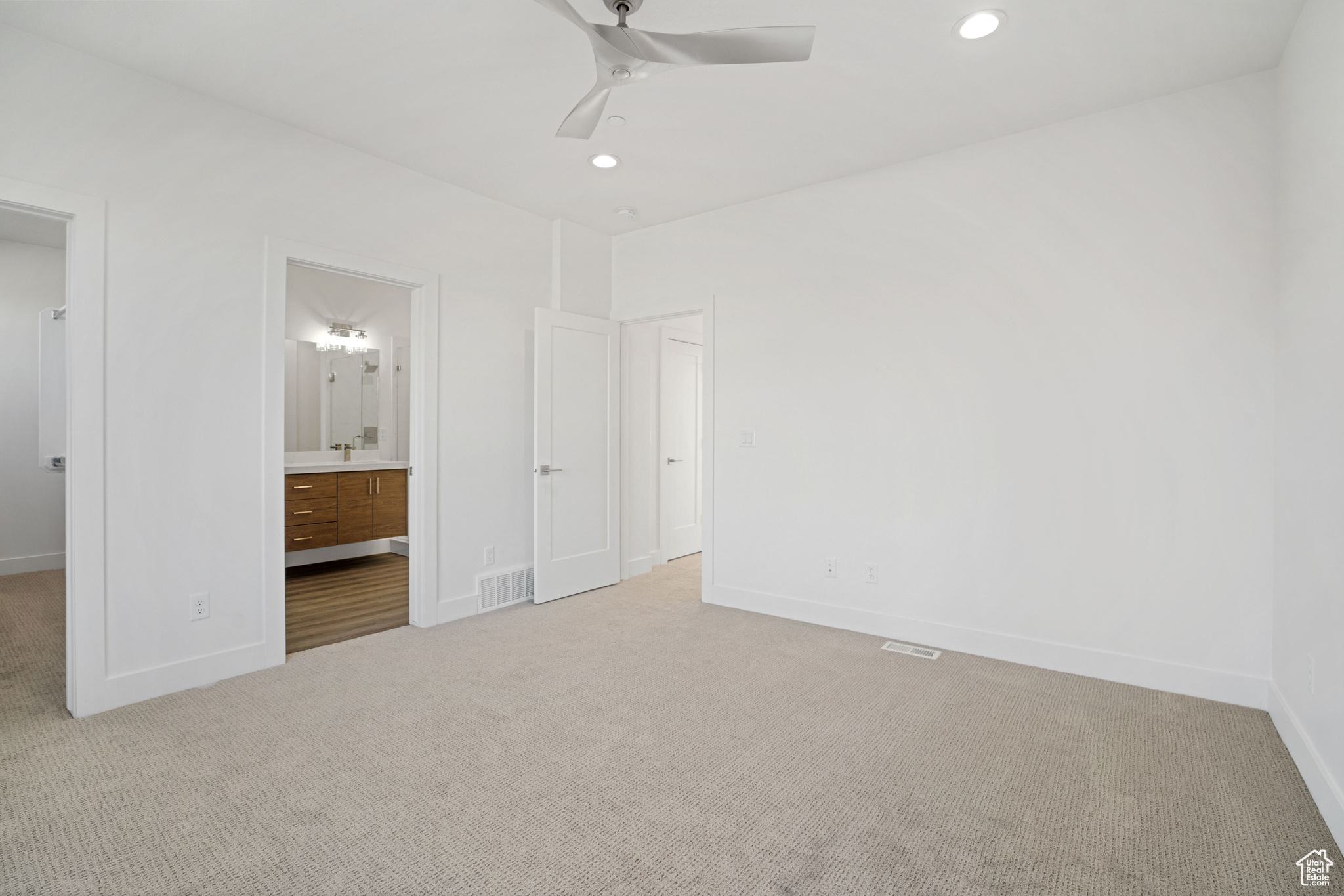 Unfurnished bedroom with light carpet, ceiling fan, and ensuite bath