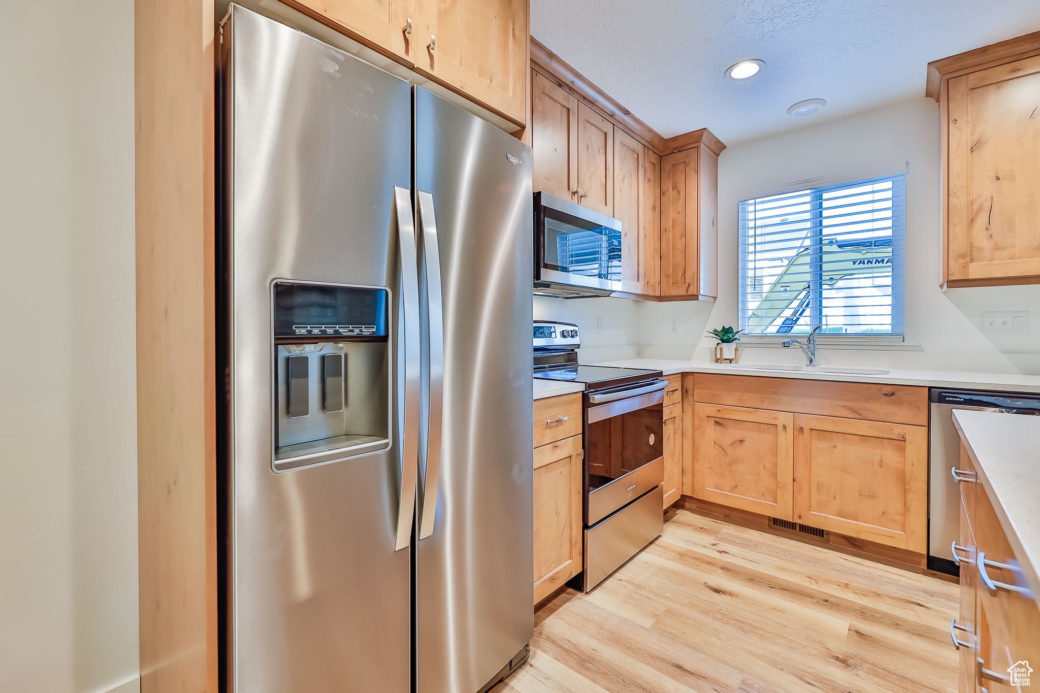 Kitchen with light wood-type flooring, appliances with stainless steel finishes, and sink