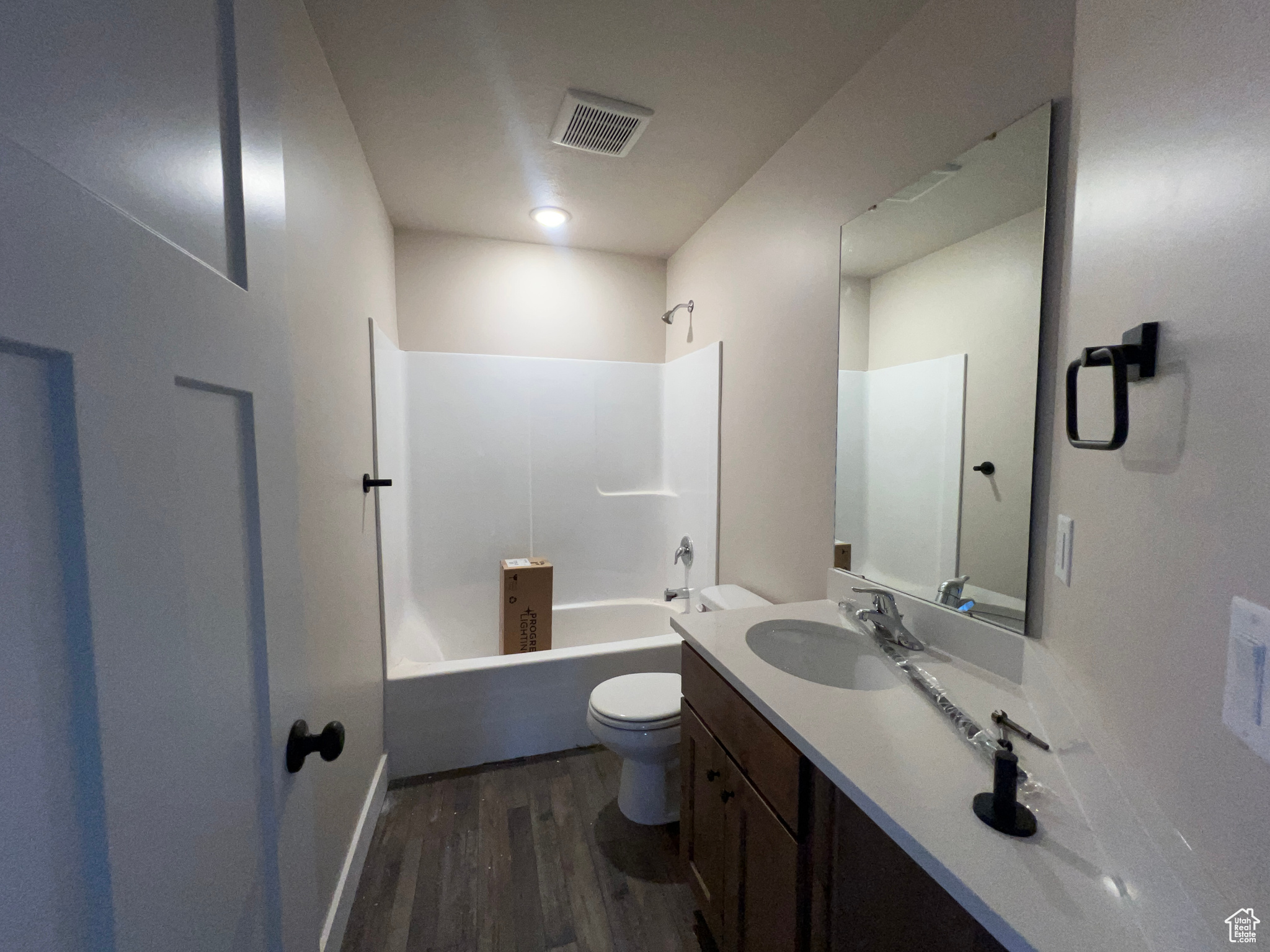 Full bathroom with vanity with extensive cabinet space, hardwood / wood-style flooring, toilet, and  shower combination
