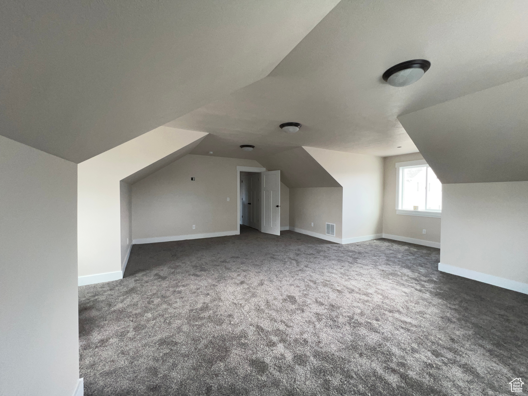 Additional living space featuring lofted ceiling and dark colored carpet