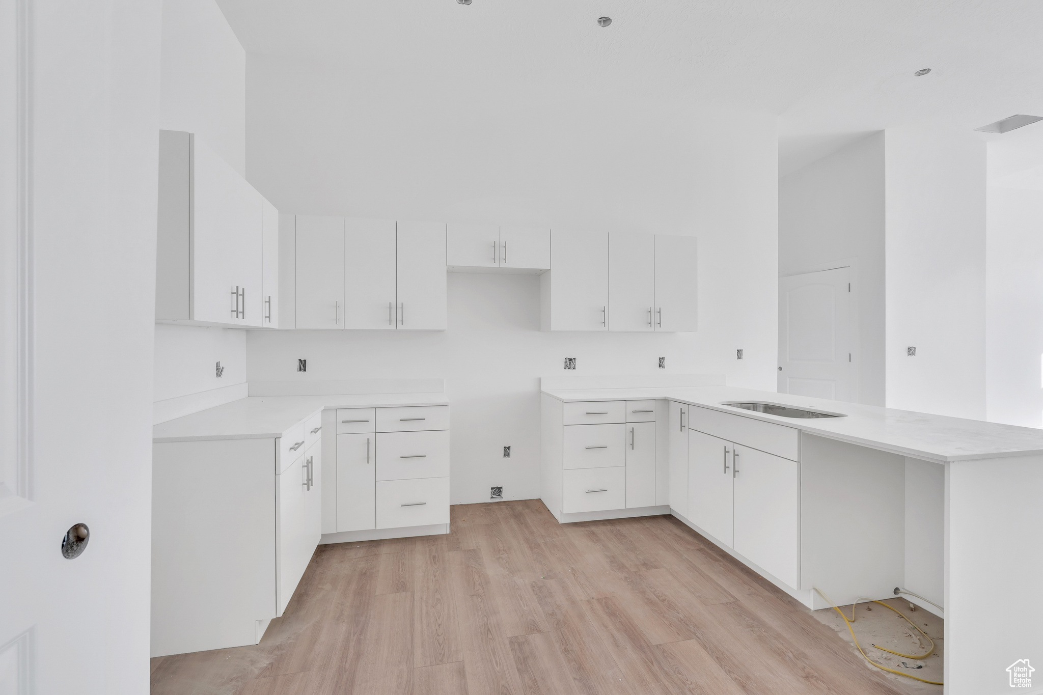 Bright white modern kitchen with quartz counters and tile backsplash.