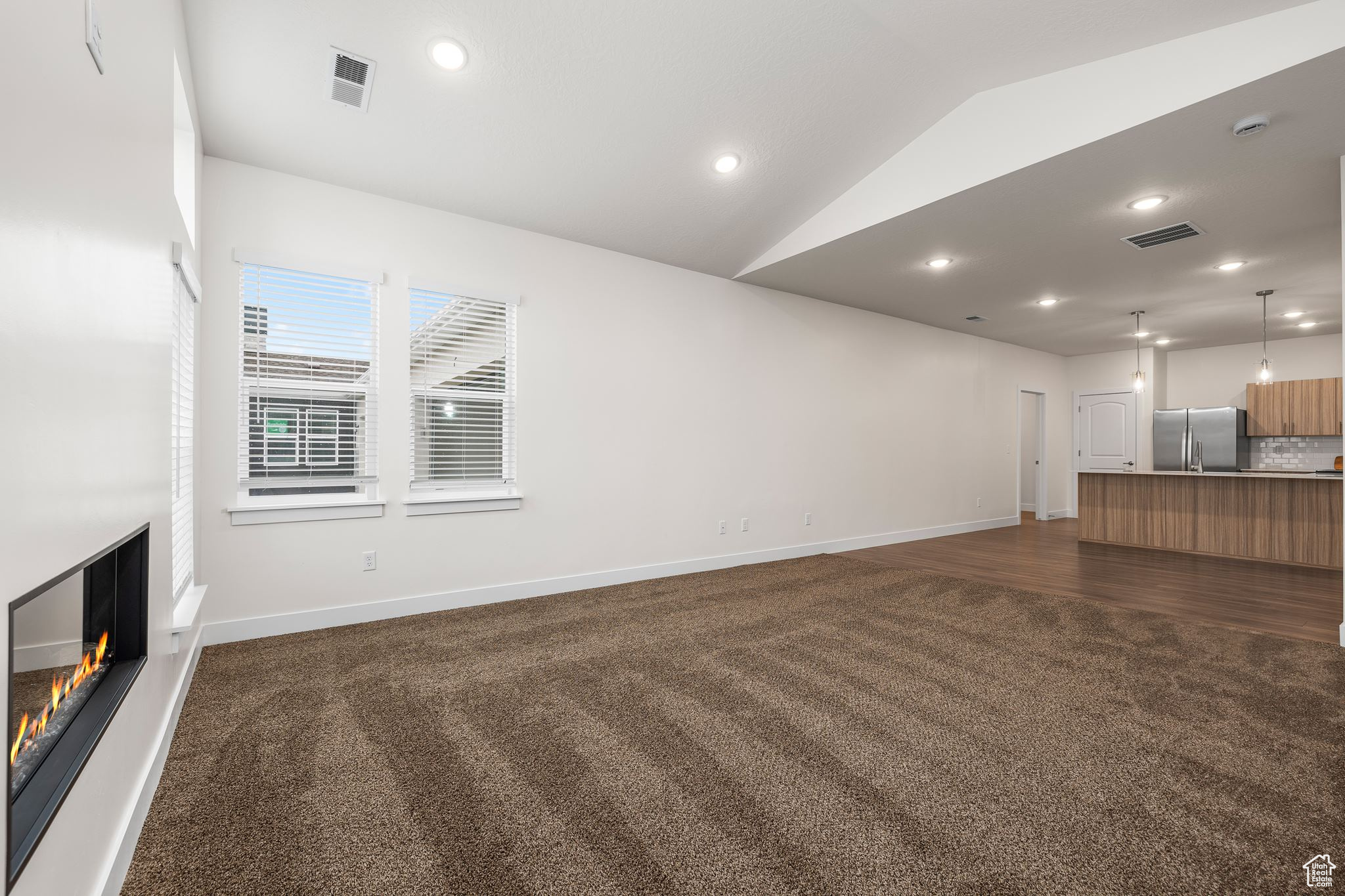 Unfurnished living room featuring dark hardwood / wood-style floors and vaulted ceiling