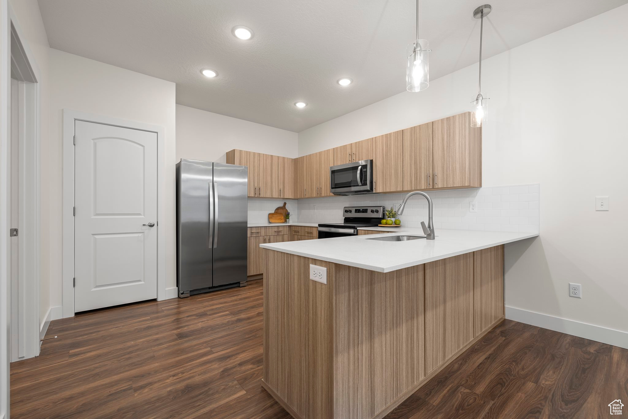 Kitchen featuring dark hardwood / wood-style flooring, sink, decorative light fixtures, and appliances with stainless steel finishes