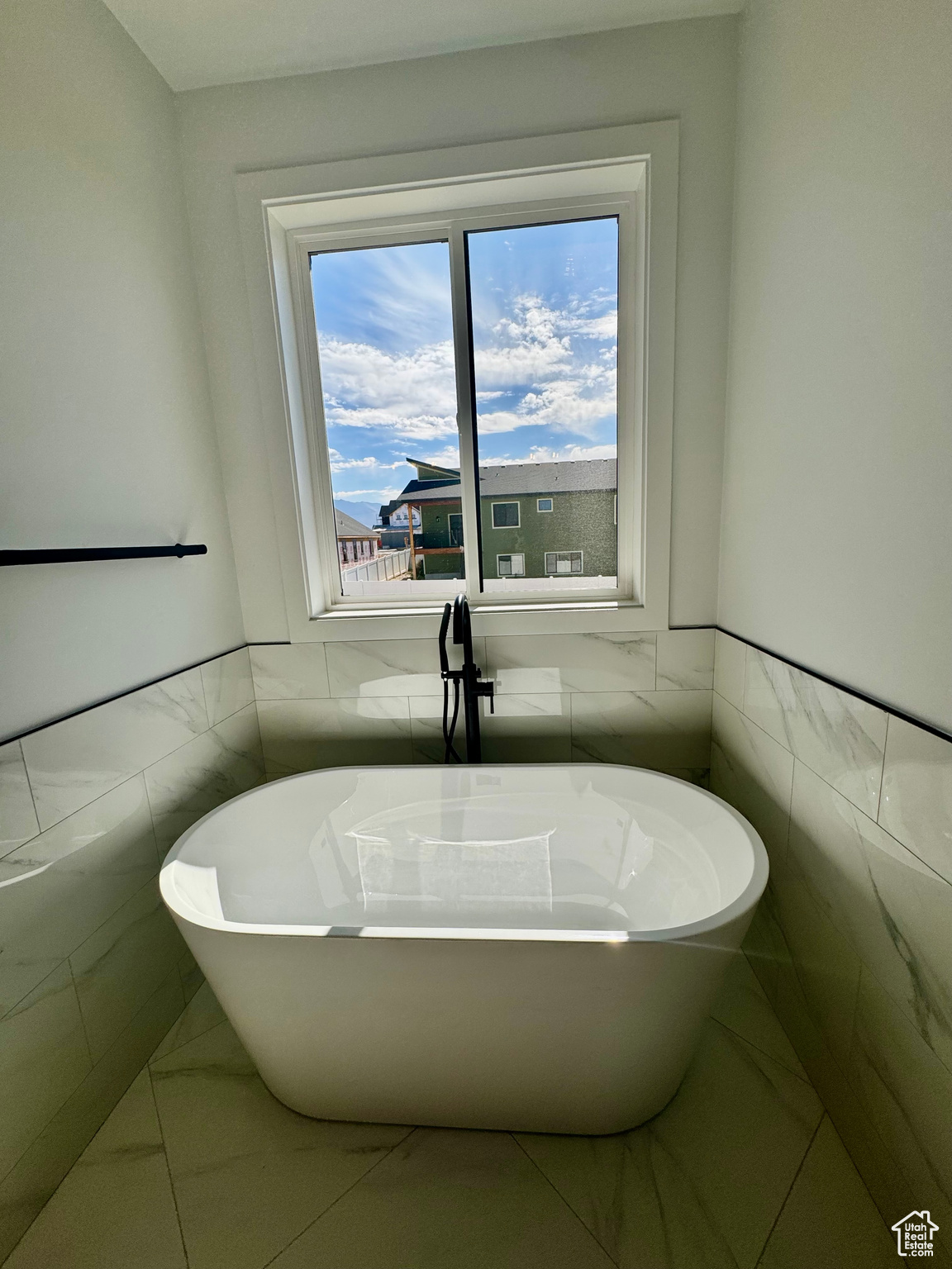 Bathroom with tile walls, a bathtub, and tile patterned floors