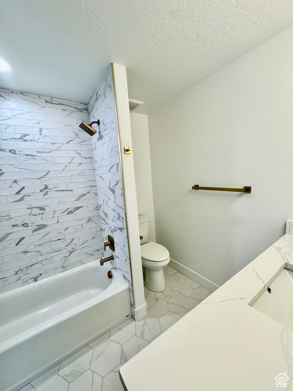 Full bathroom with vanity, tiled shower / bath, a textured ceiling, and toilet