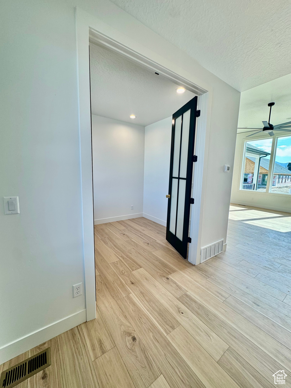 Unfurnished room featuring a textured ceiling, ceiling fan, and light hardwood / wood-style flooring