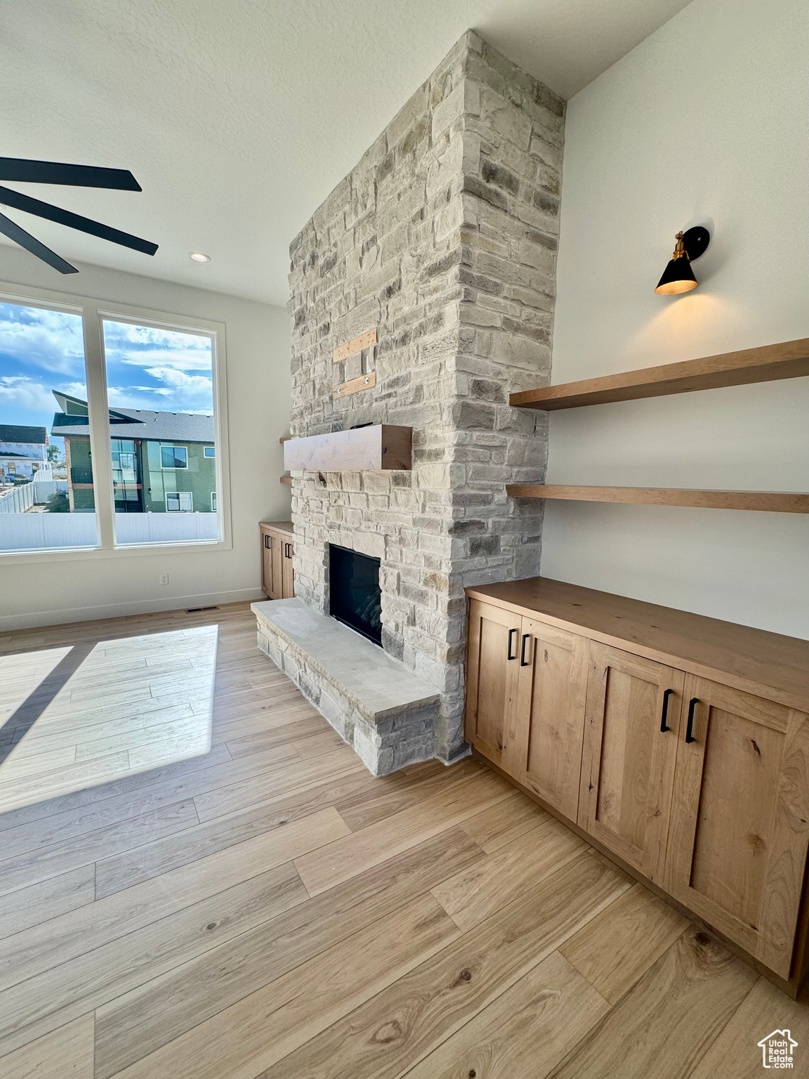 Unfurnished living room featuring ceiling fan, a fireplace, and light hardwood / wood-style floors