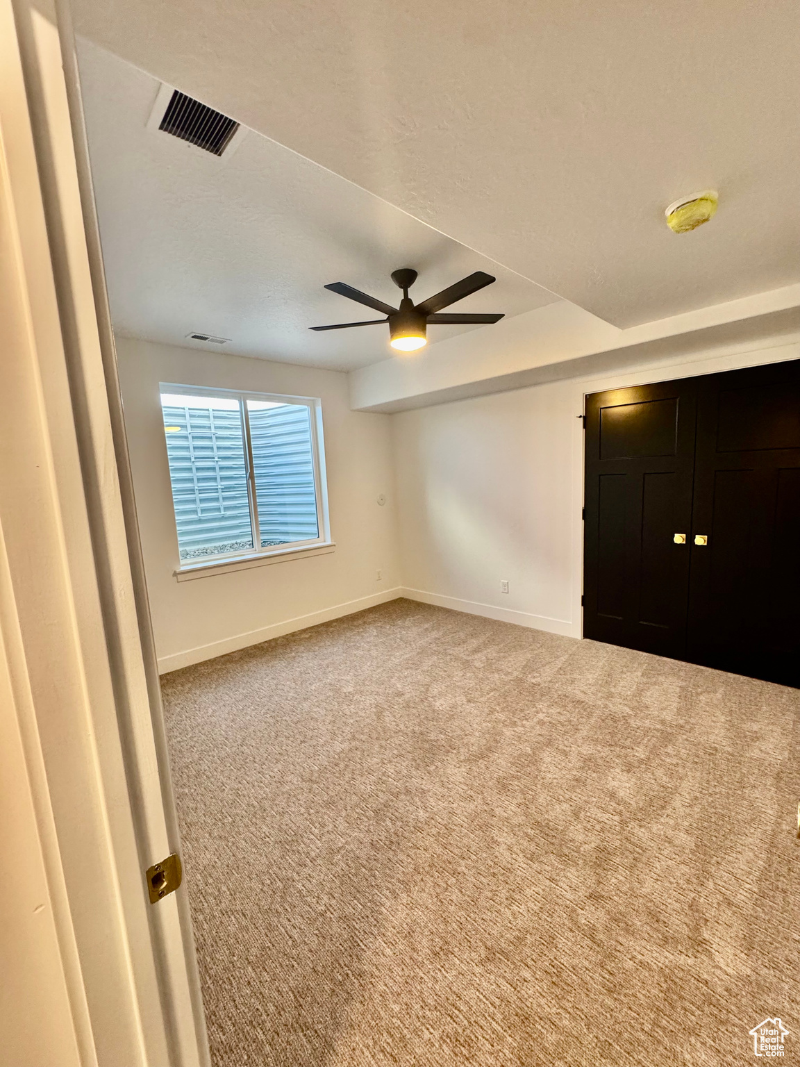 Carpeted spare room featuring ceiling fan