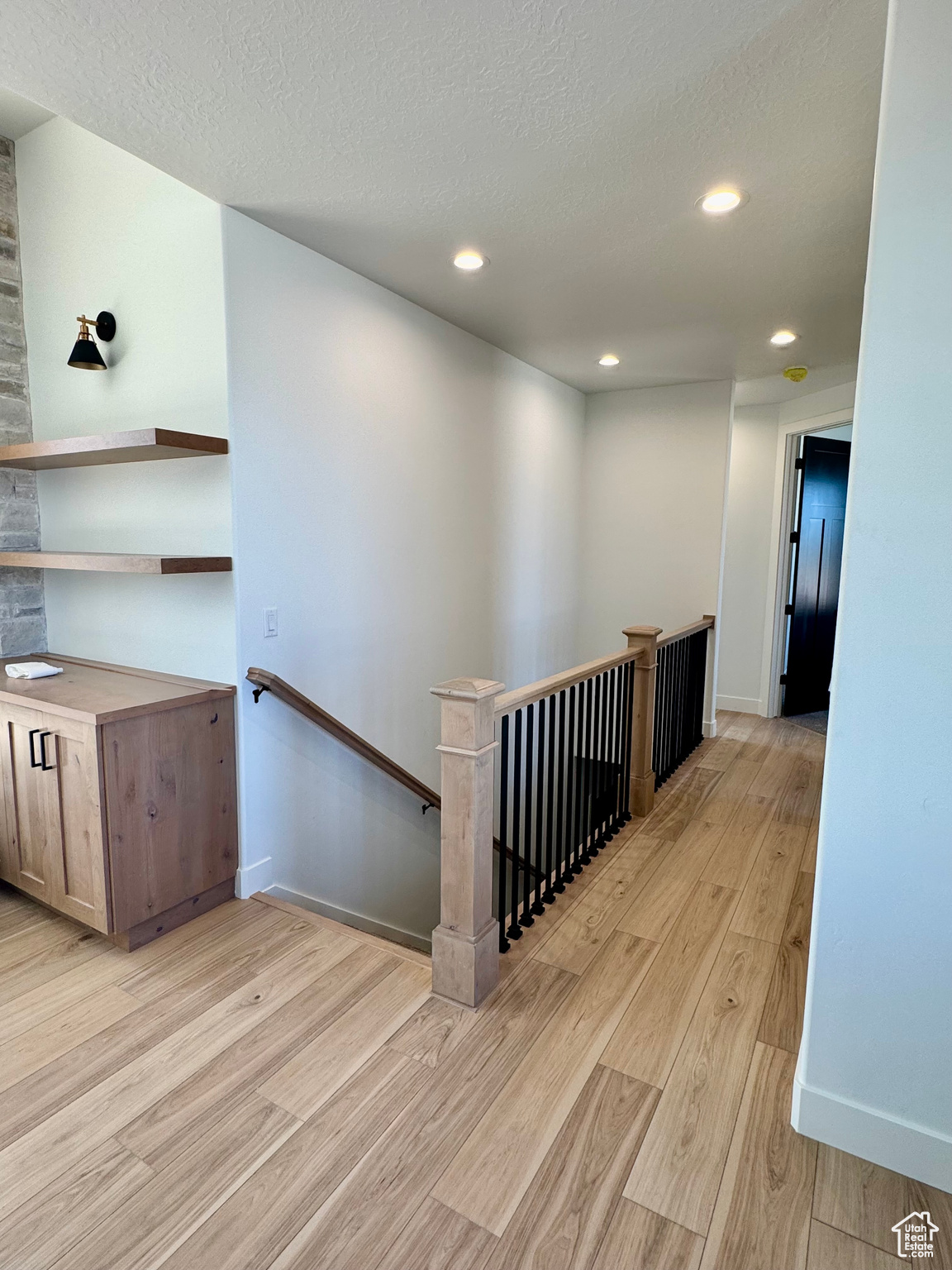 Hall featuring light wood-type flooring and a textured ceiling