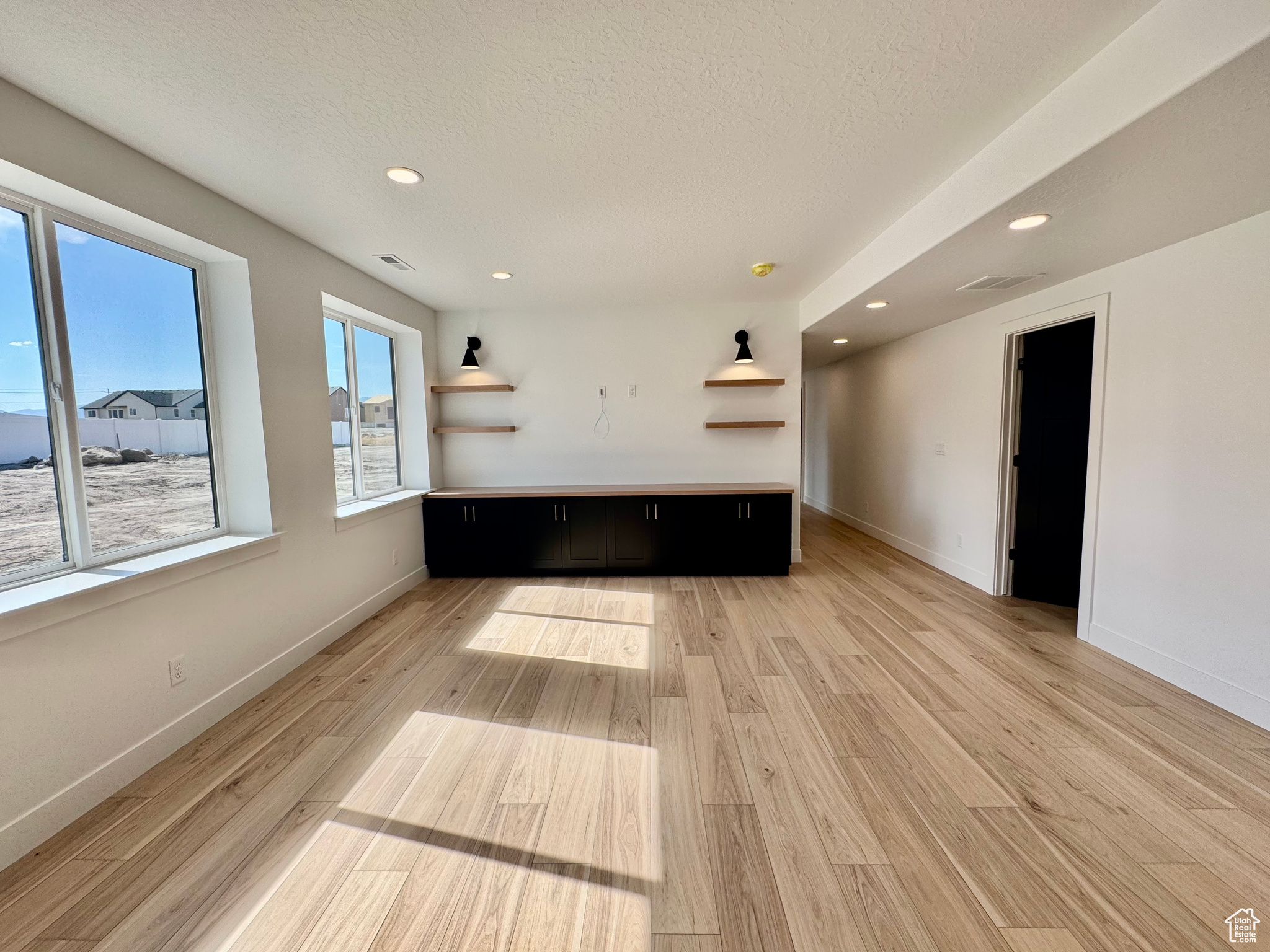 Unfurnished living room featuring light wood-type flooring and a textured ceiling