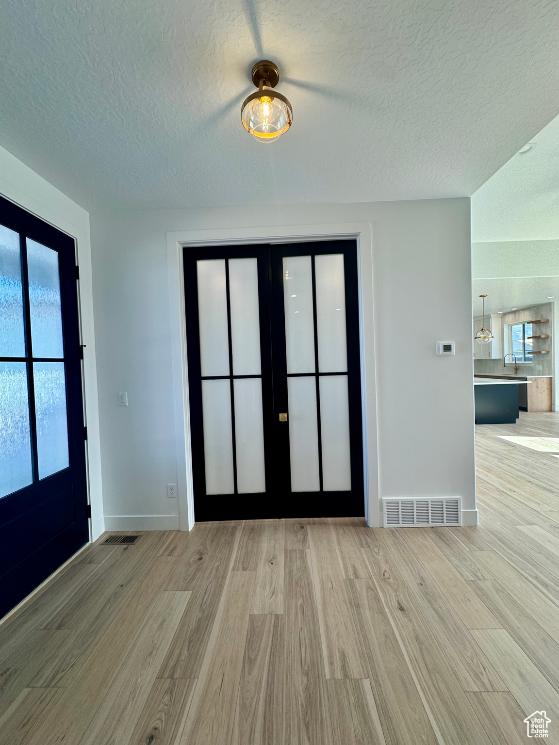 Entryway with light hardwood / wood-style floors, french doors, and a textured ceiling