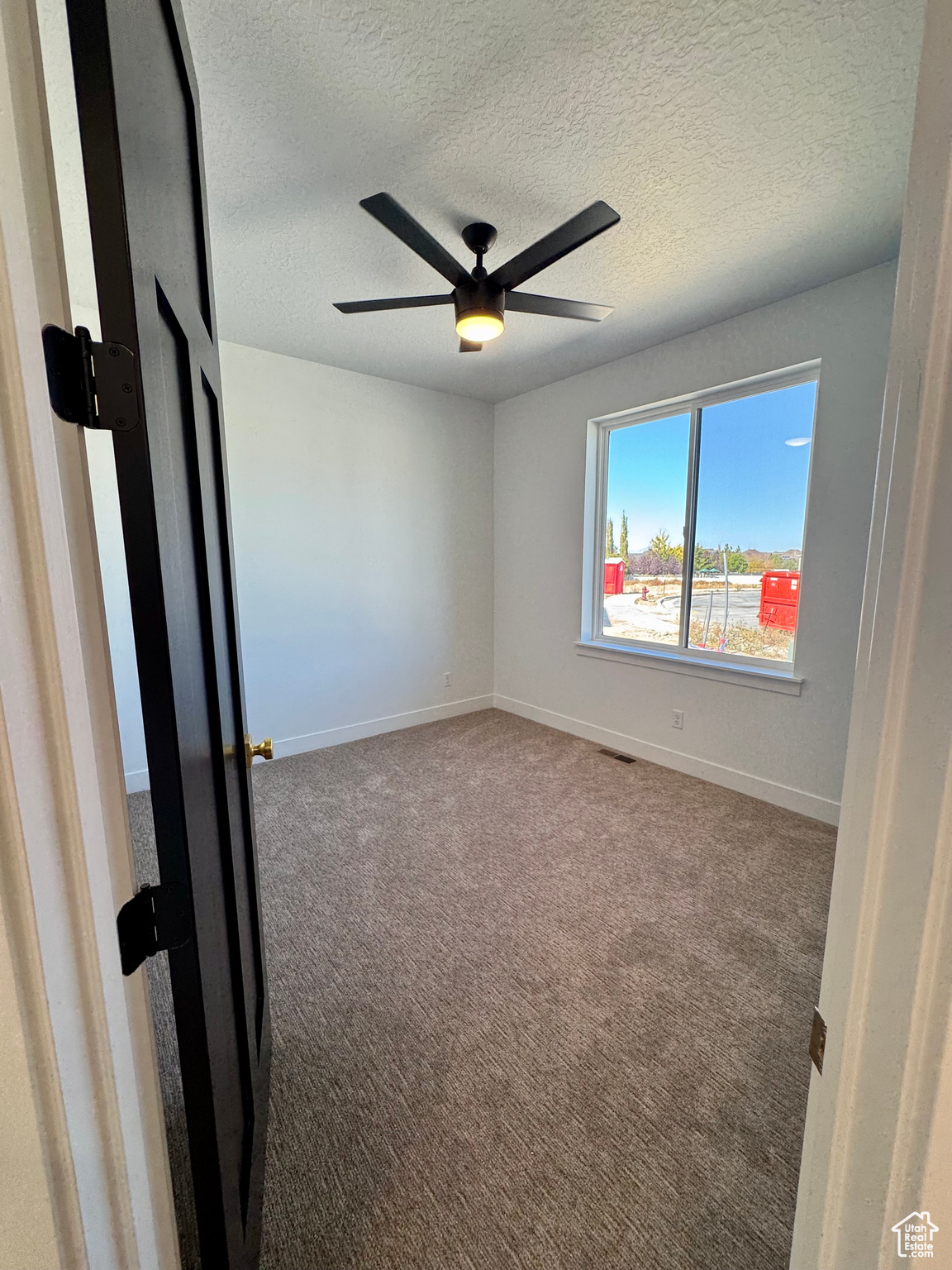 Carpeted spare room with ceiling fan and a textured ceiling