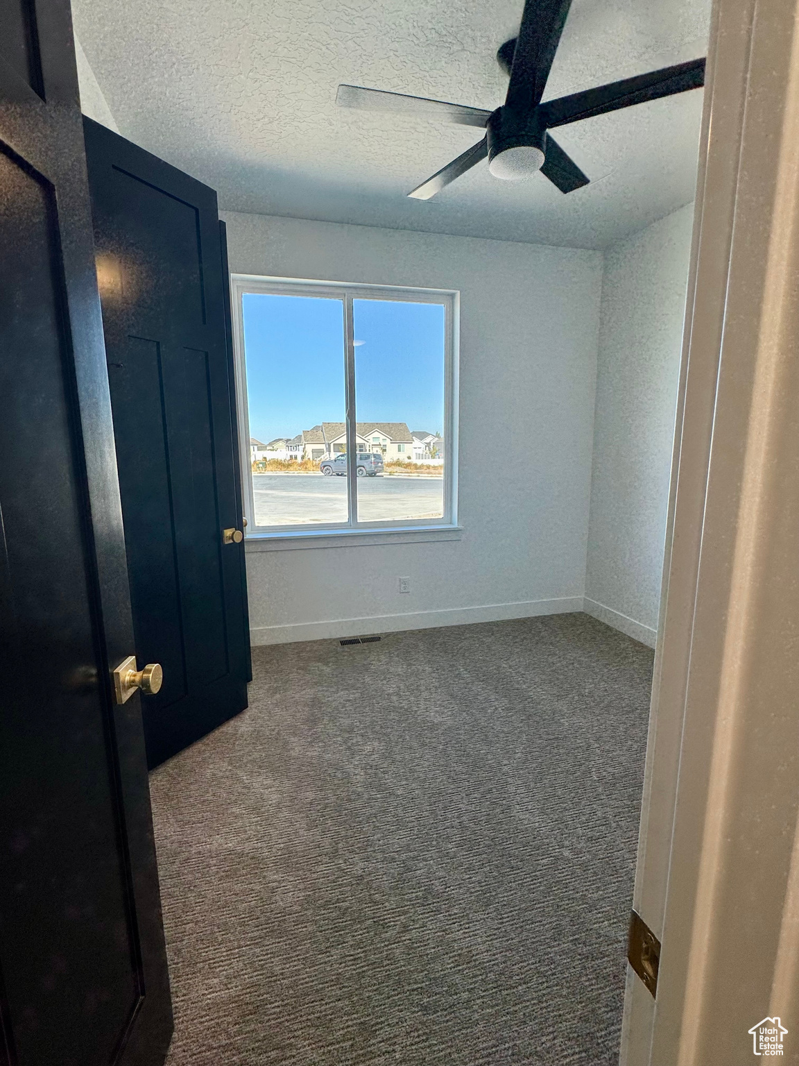 Spare room with ceiling fan, a textured ceiling, and carpet flooring