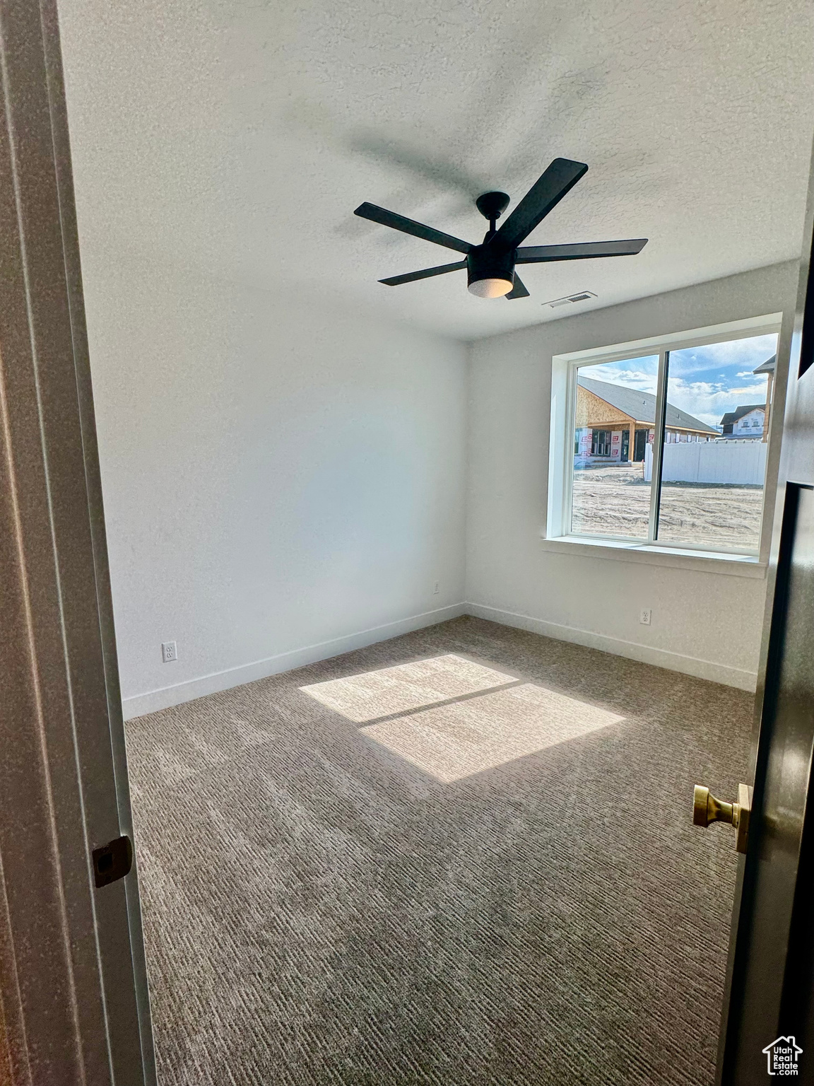 Spare room featuring a textured ceiling, carpet floors, and ceiling fan