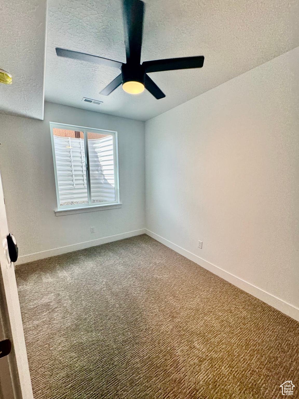 Spare room with ceiling fan, a textured ceiling, and carpet