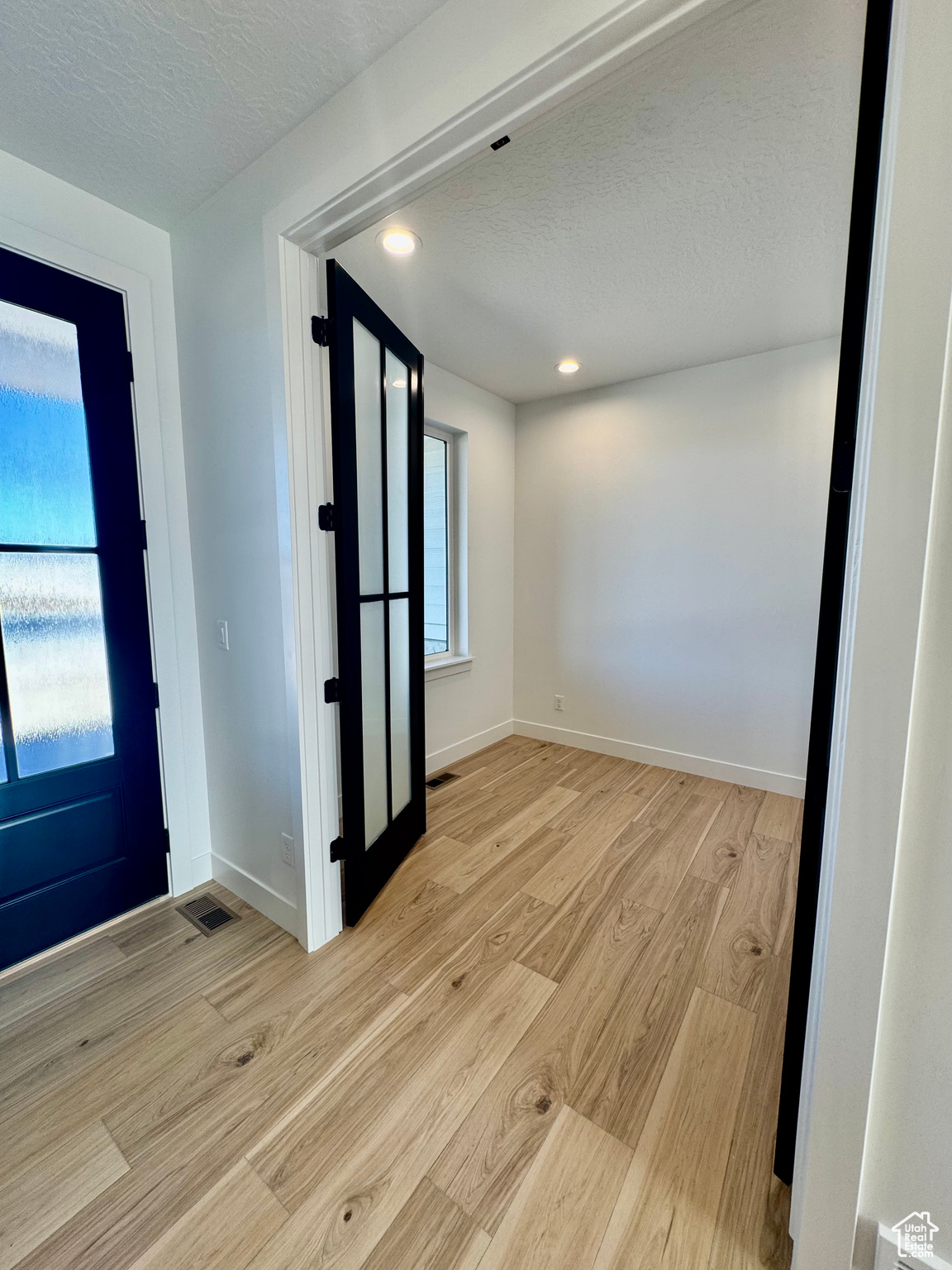 Foyer with a textured ceiling and light hardwood / wood-style flooring