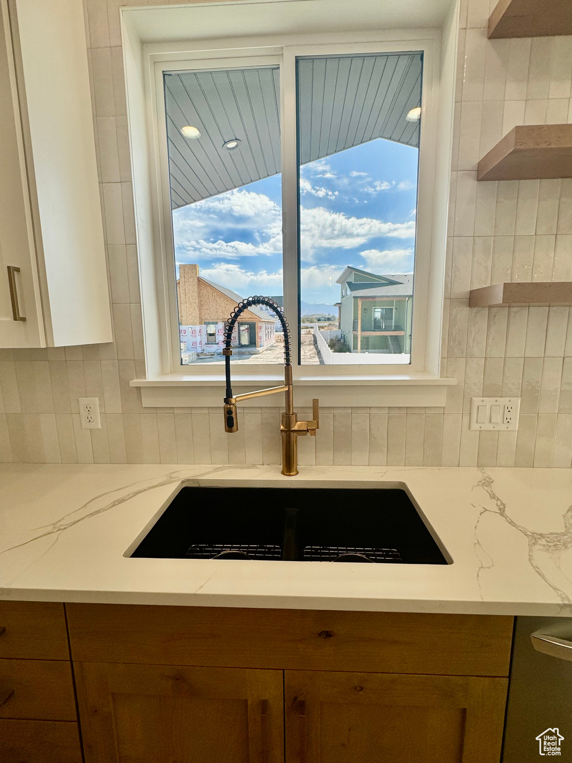 Kitchen with decorative backsplash, sink, and light stone counters