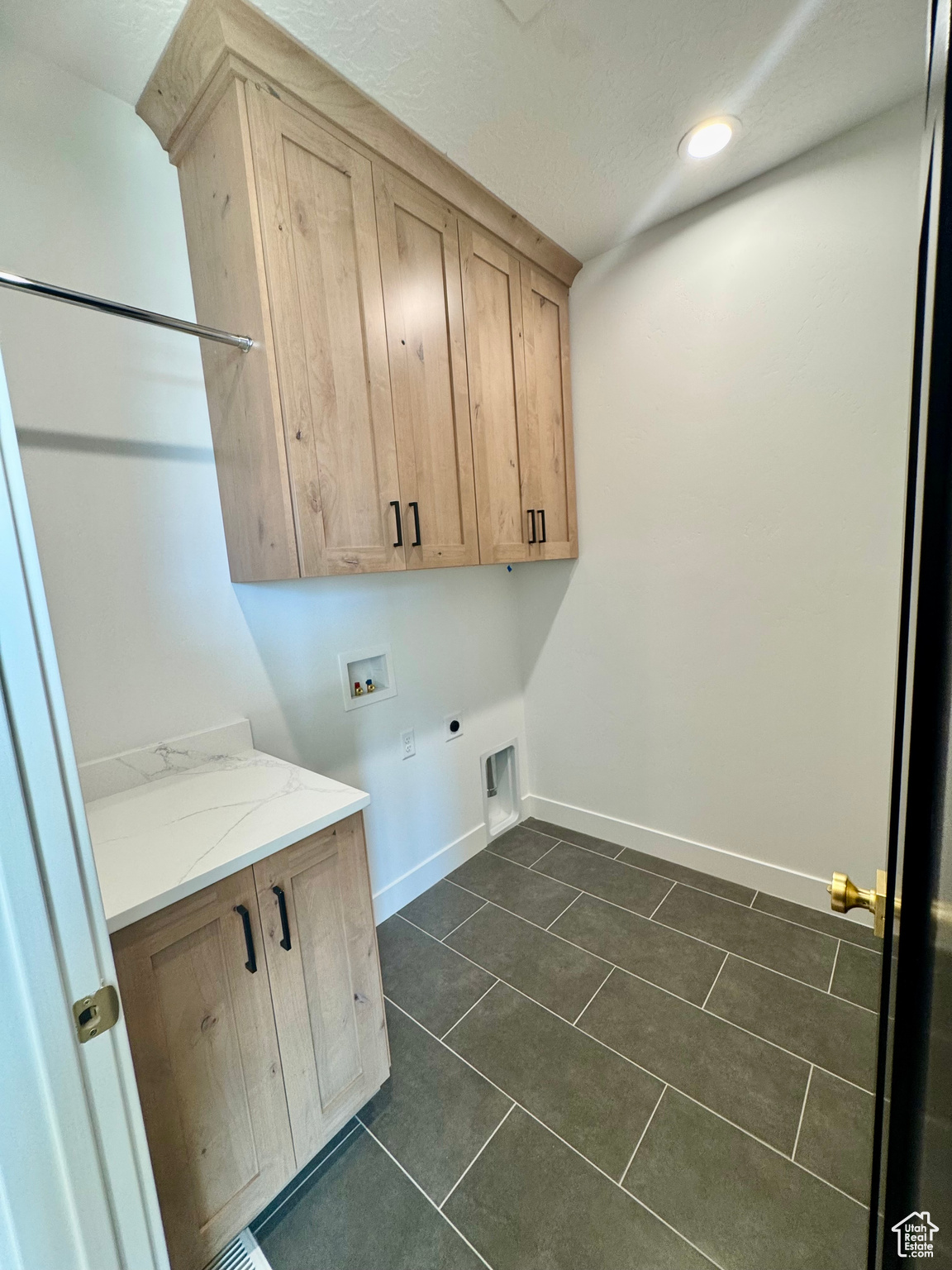 Washroom featuring hookup for a washing machine, hookup for an electric dryer, dark tile patterned floors, and cabinets