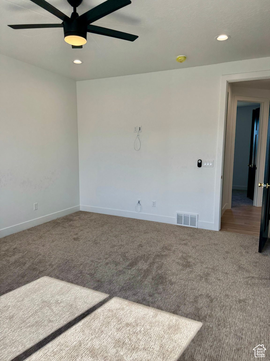 Carpeted spare room featuring ceiling fan