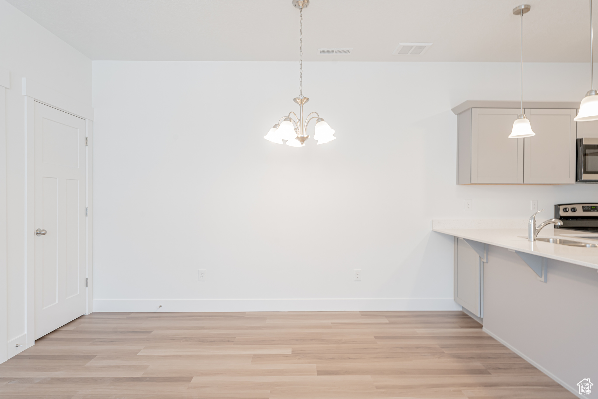 Unfurnished dining area with sink, a chandelier, and light hardwood / wood-style floors