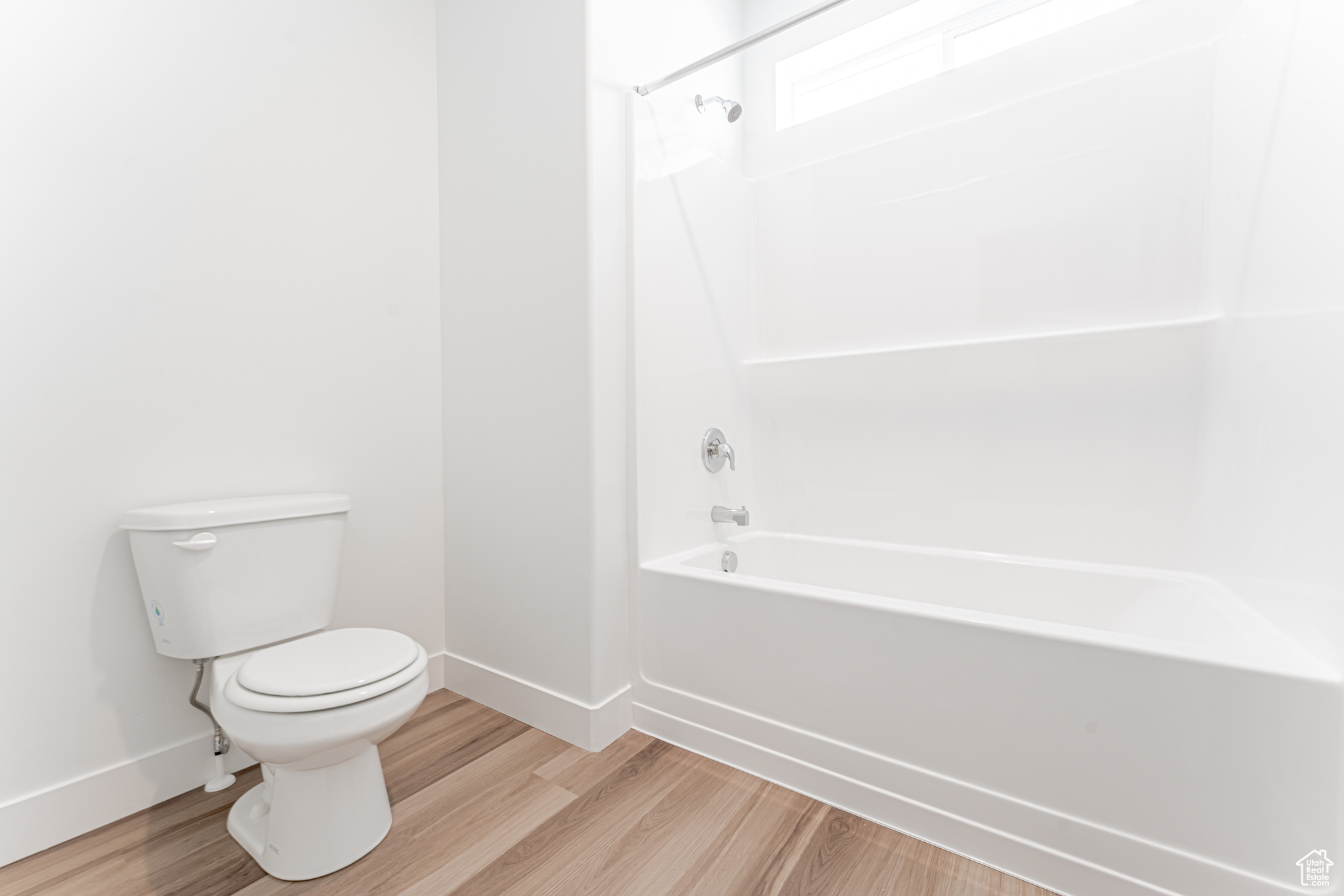 Bathroom with toilet, wood-type flooring, and shower / washtub combination