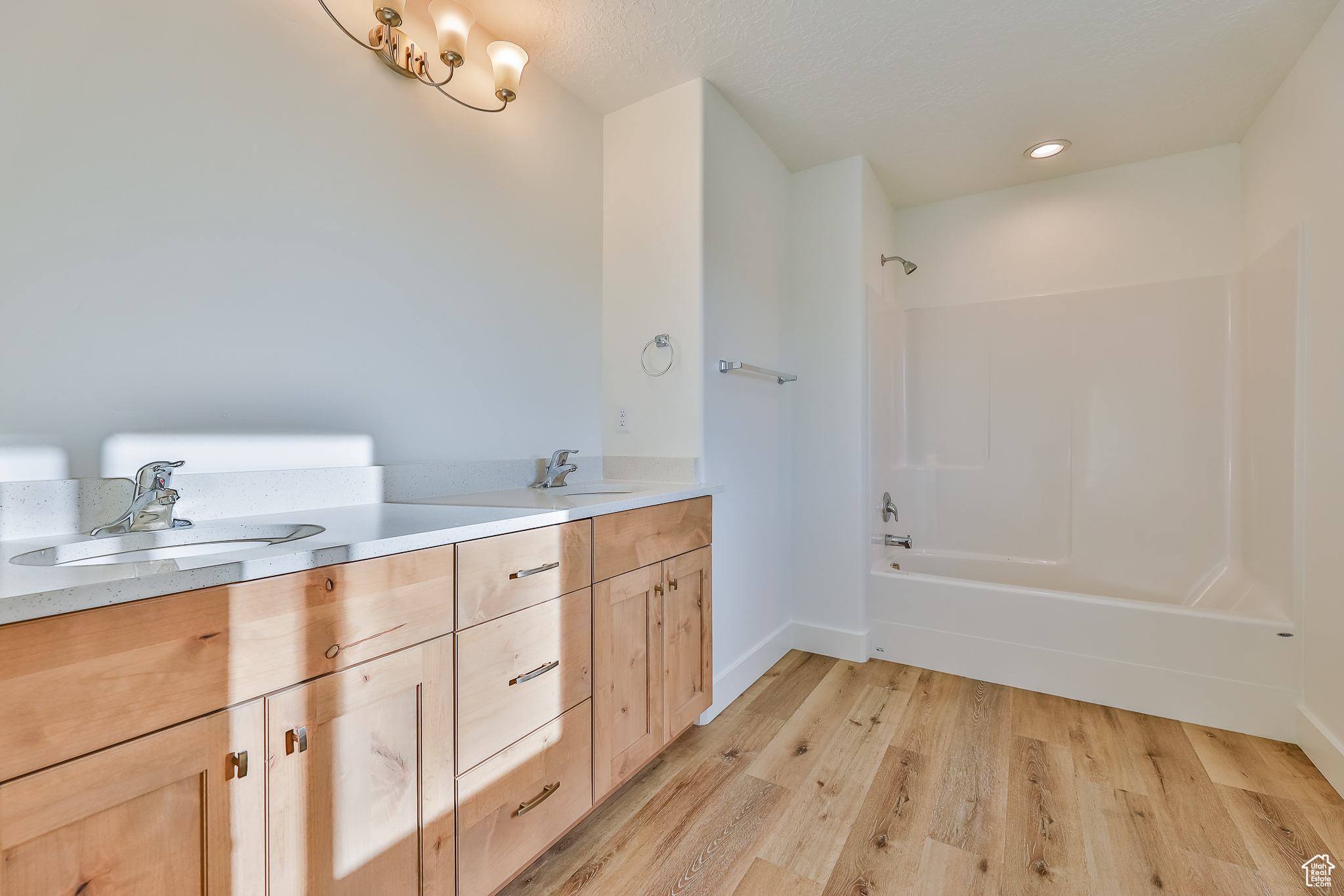 Bathroom with dual vanity, tub / shower combination, and wood-type flooring