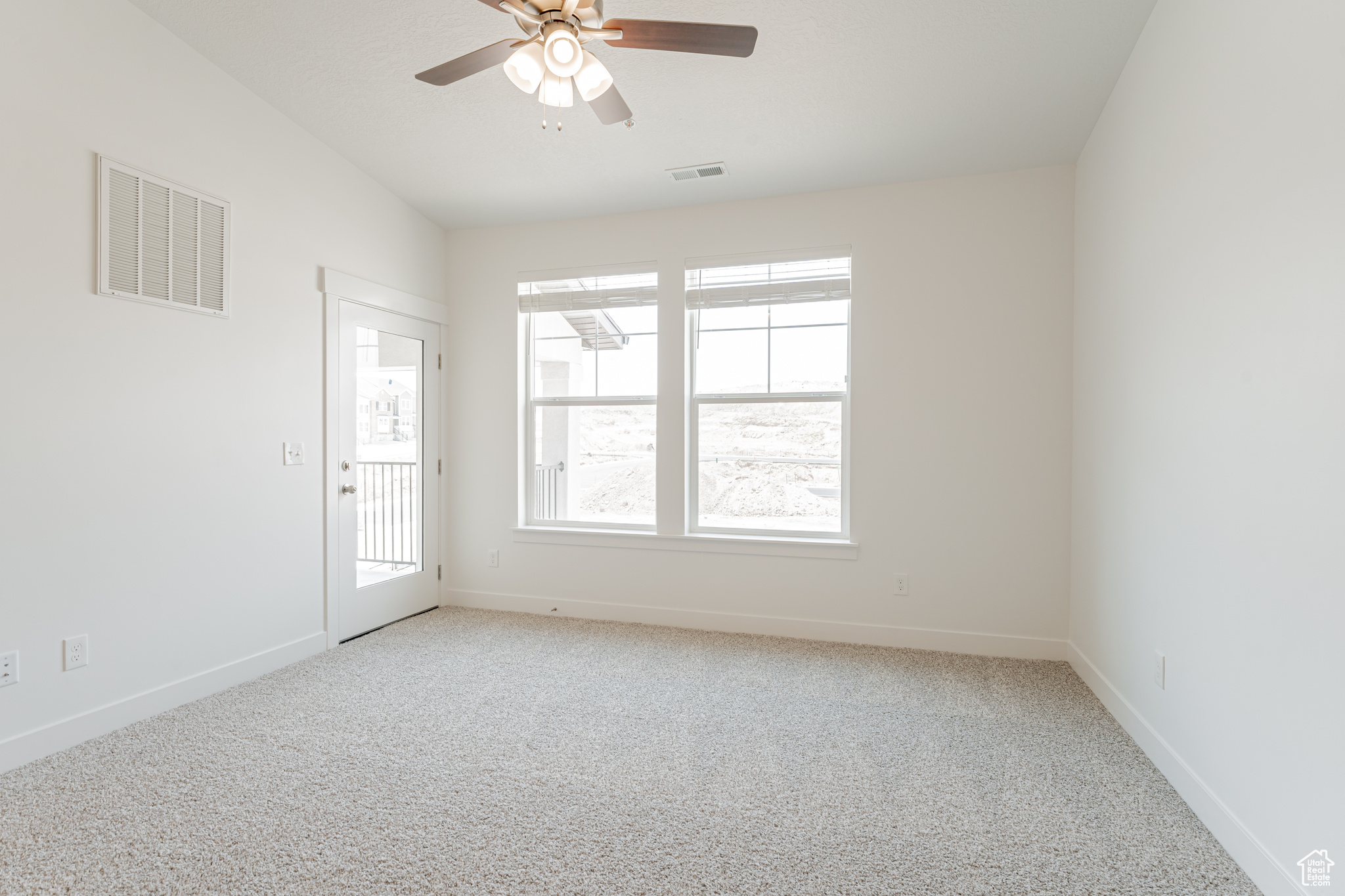 Carpeted spare room featuring ceiling fan and plenty of natural light