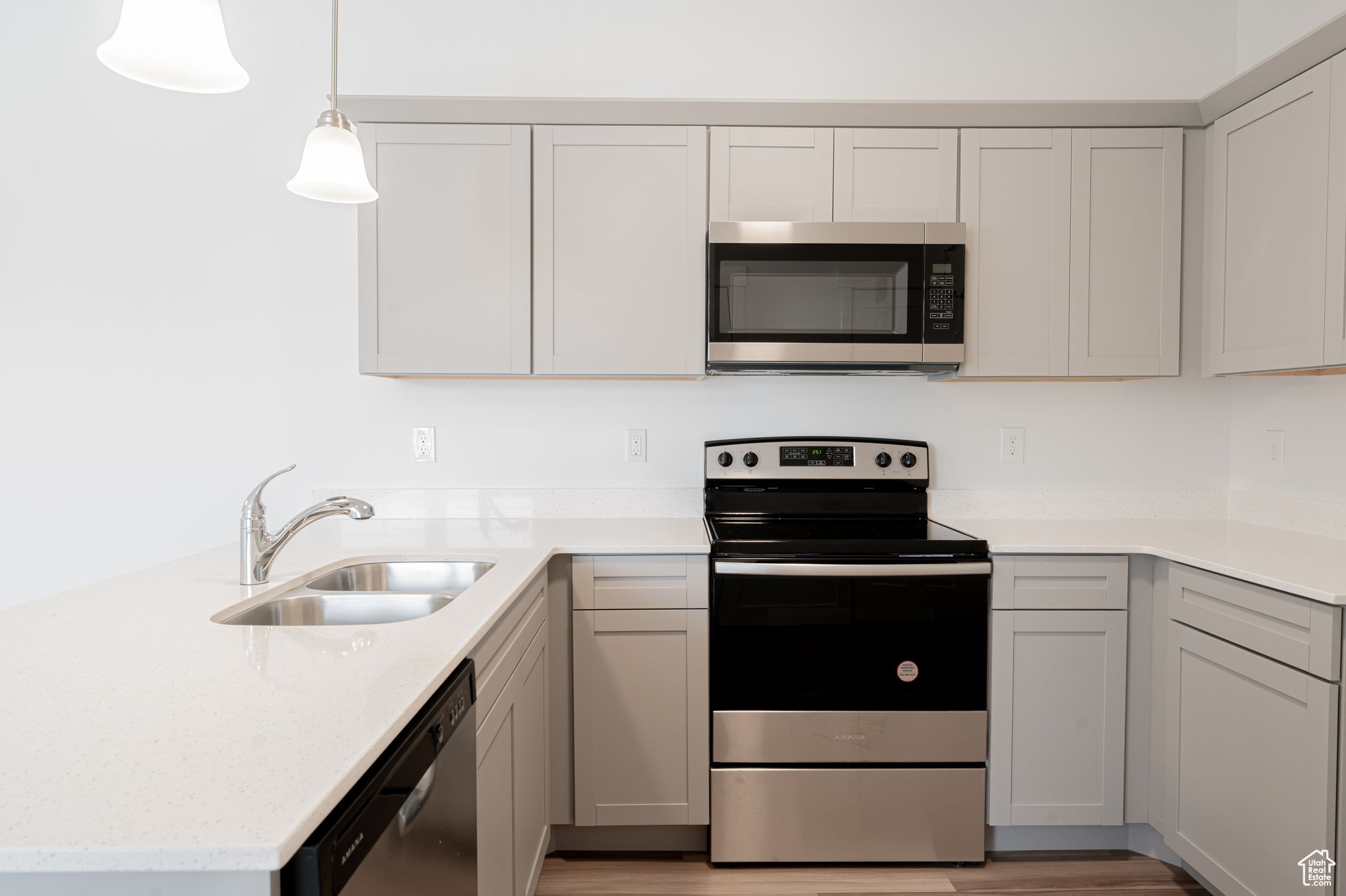 Kitchen with gray cabinets, sink, stainless steel appliances, and light hardwood / wood-style floors