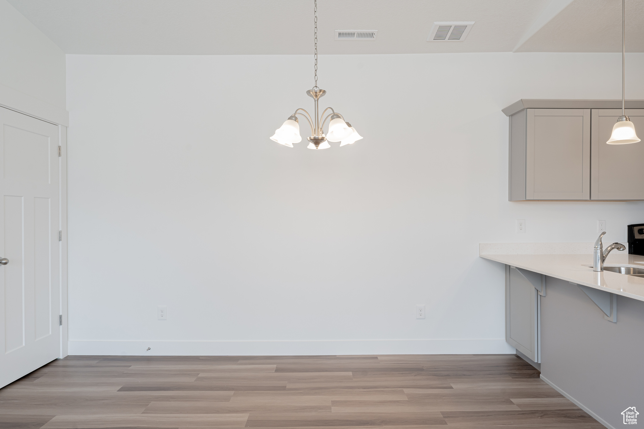 Unfurnished dining area featuring light hardwood / wood-style flooring, sink, and a chandelier