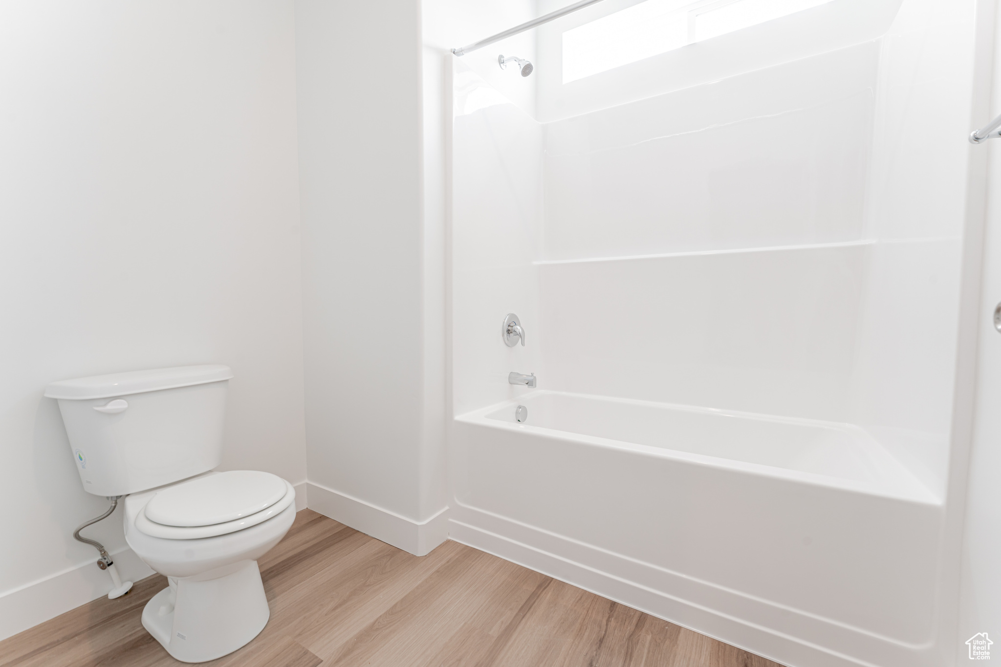 Bathroom with washtub / shower combination, toilet, and wood-type flooring