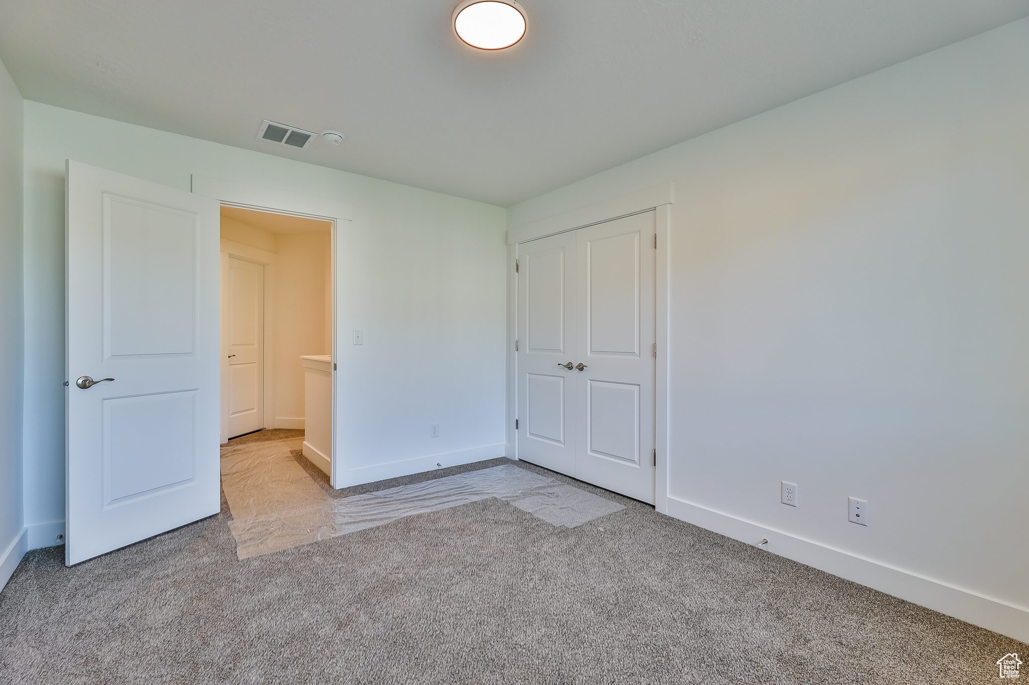 Unfurnished bedroom with light colored carpet and a closet