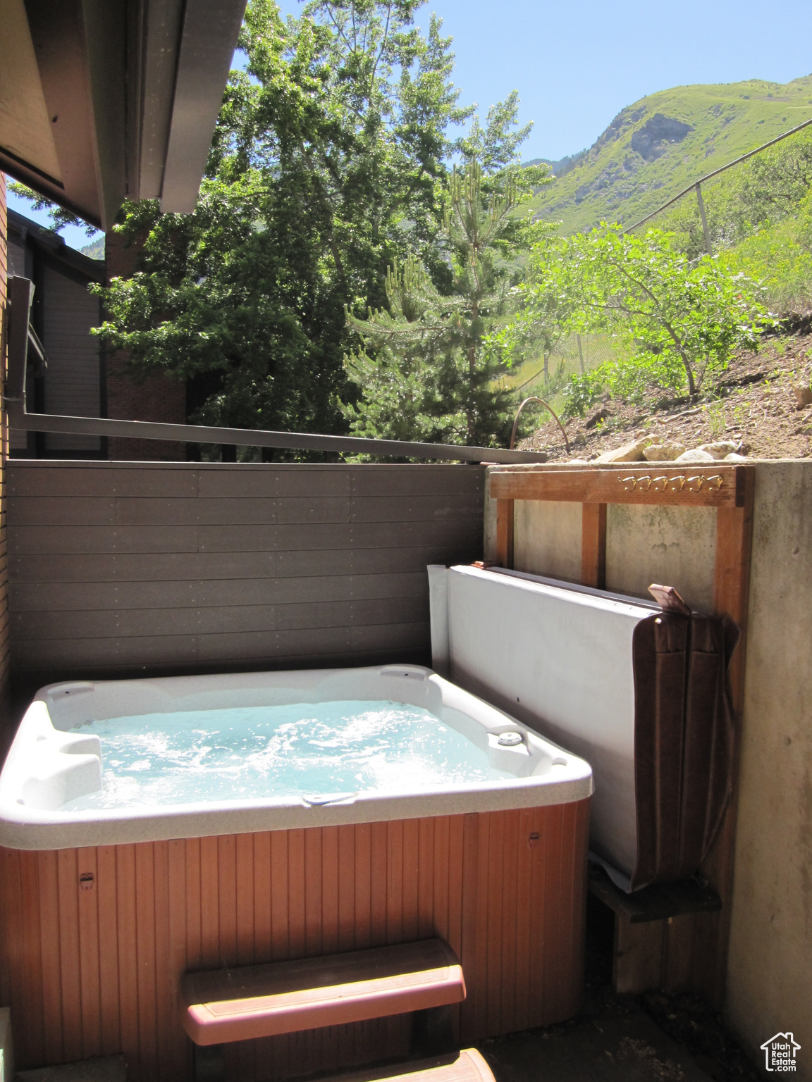 View of patio with a mountain view and a hot tub. Hot tub can be running and serviced for a $200 additional monthly fee.