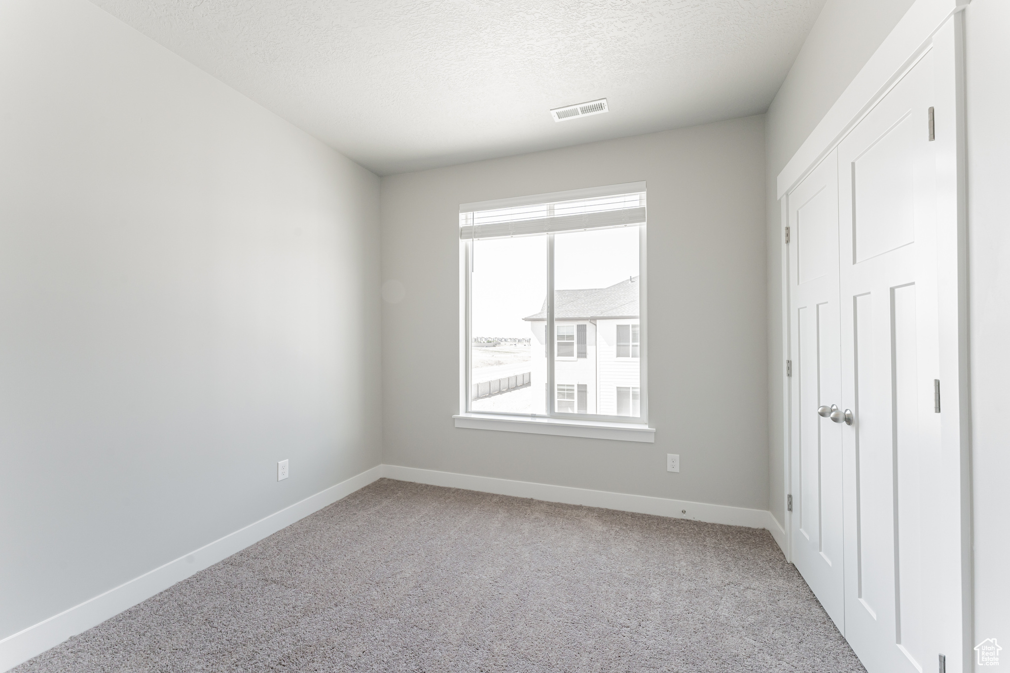 Unfurnished bedroom with light carpet and a textured ceiling