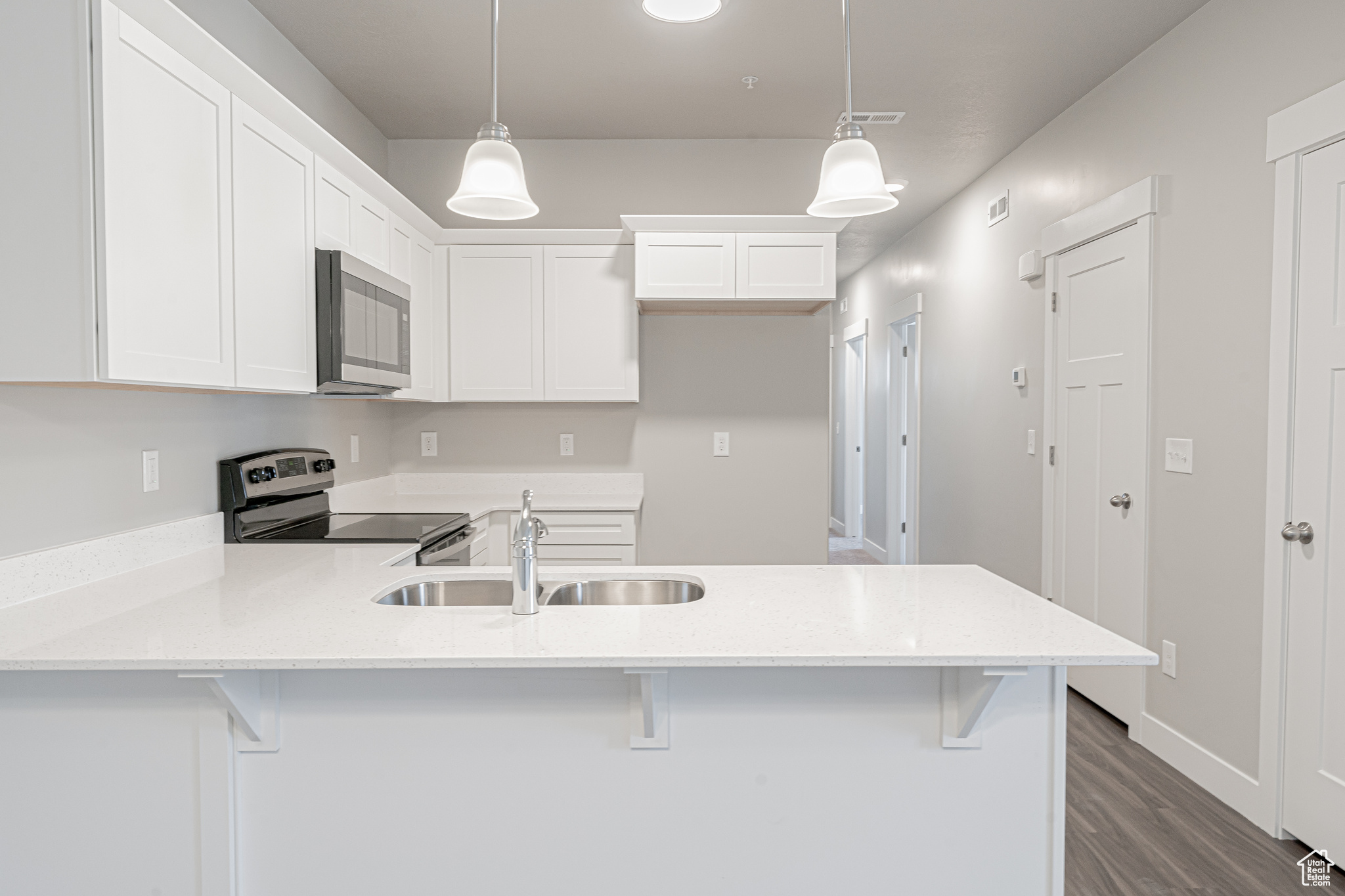 Kitchen with hanging light fixtures, a breakfast bar, sink, and appliances with stainless steel finishes