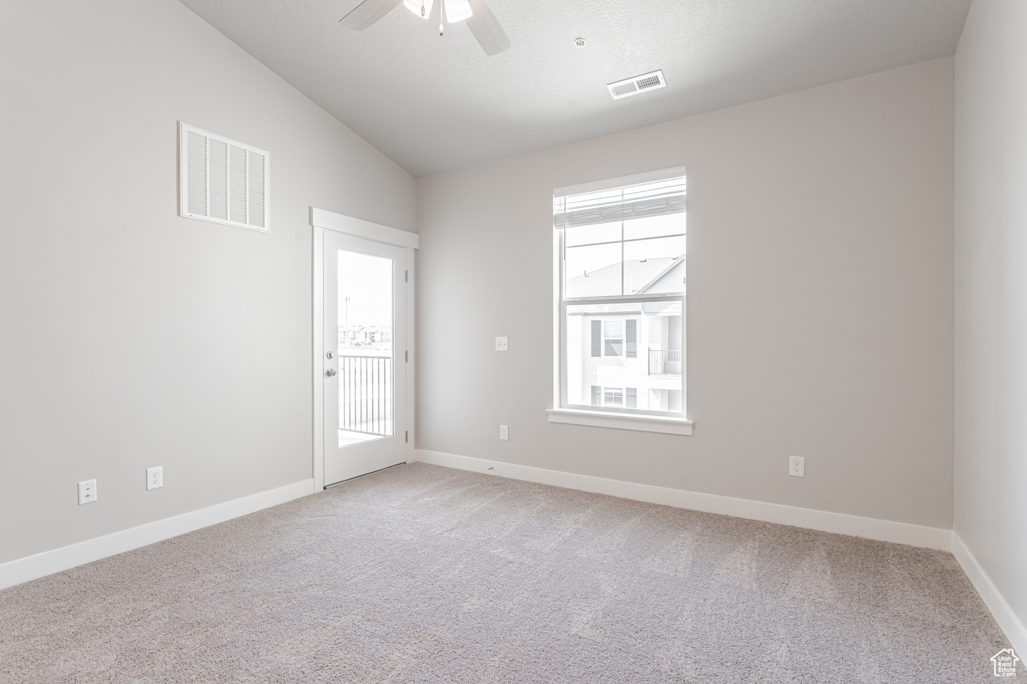 Empty room featuring ceiling fan, light colored carpet, and vaulted ceiling