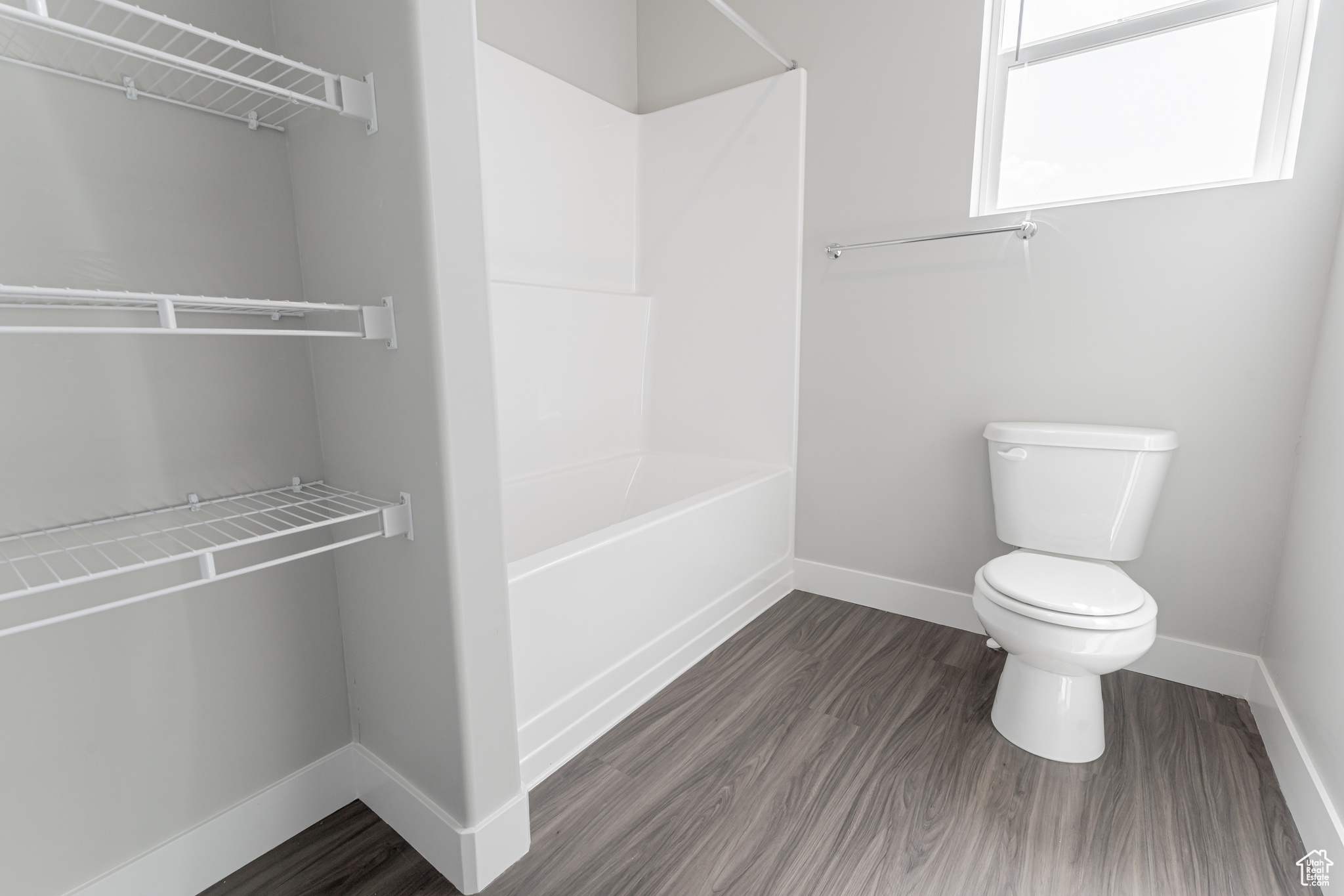 Bathroom with hardwood / wood-style floors, toilet, and shower / washtub combination