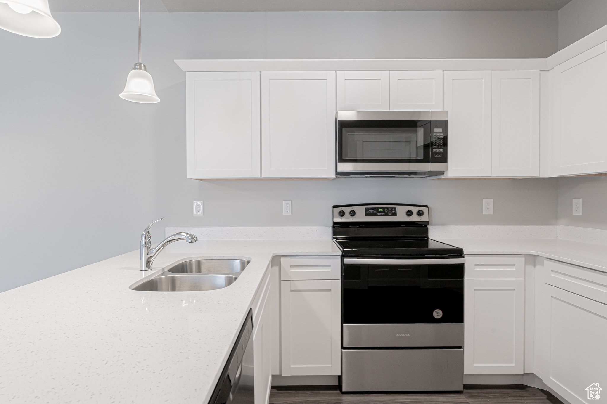 Kitchen with white cabinetry, sink, hanging light fixtures, dark hardwood / wood-style floors, and appliances with stainless steel finishes