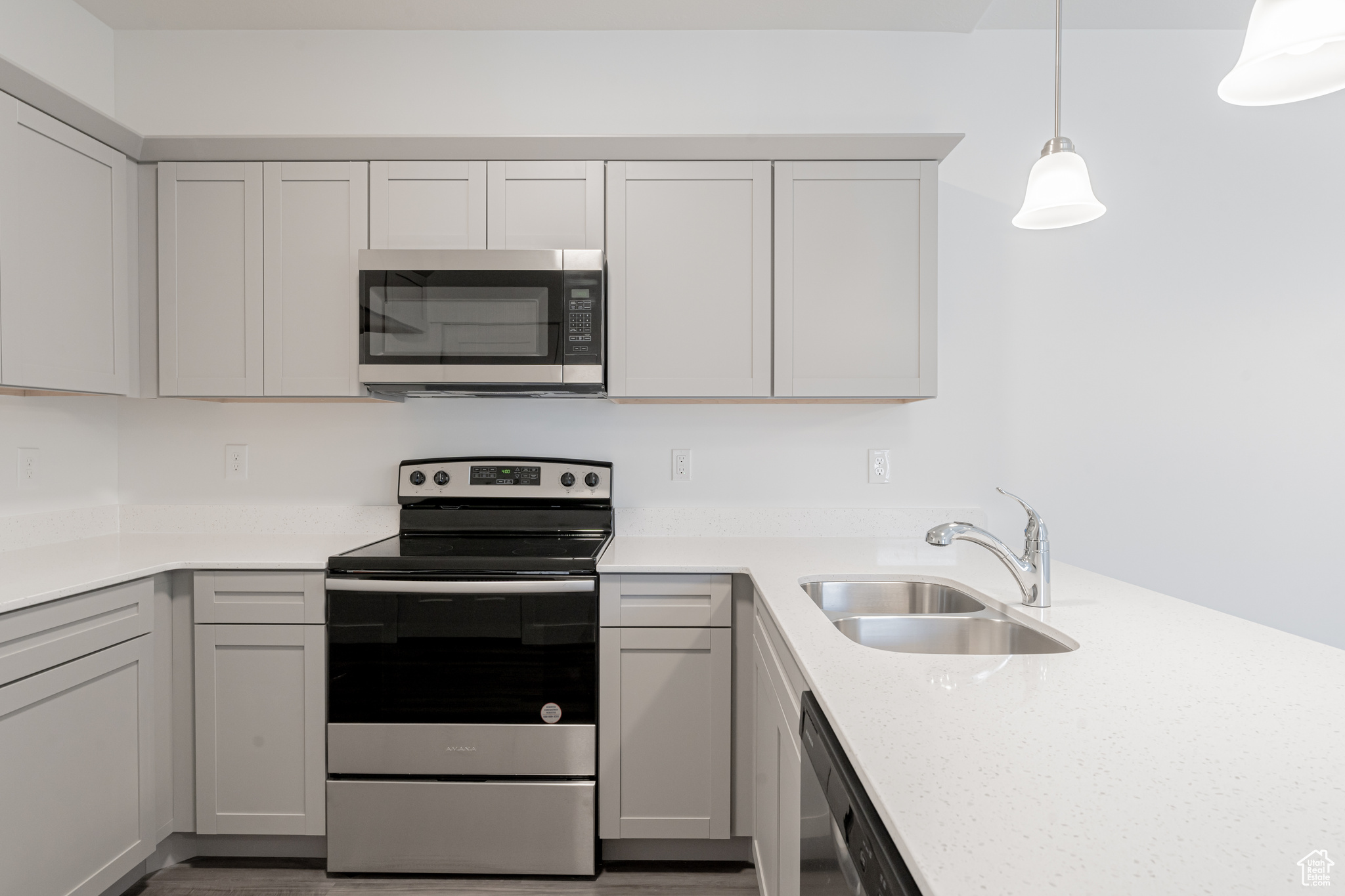 Kitchen with appliances with stainless steel finishes, decorative light fixtures, and sink