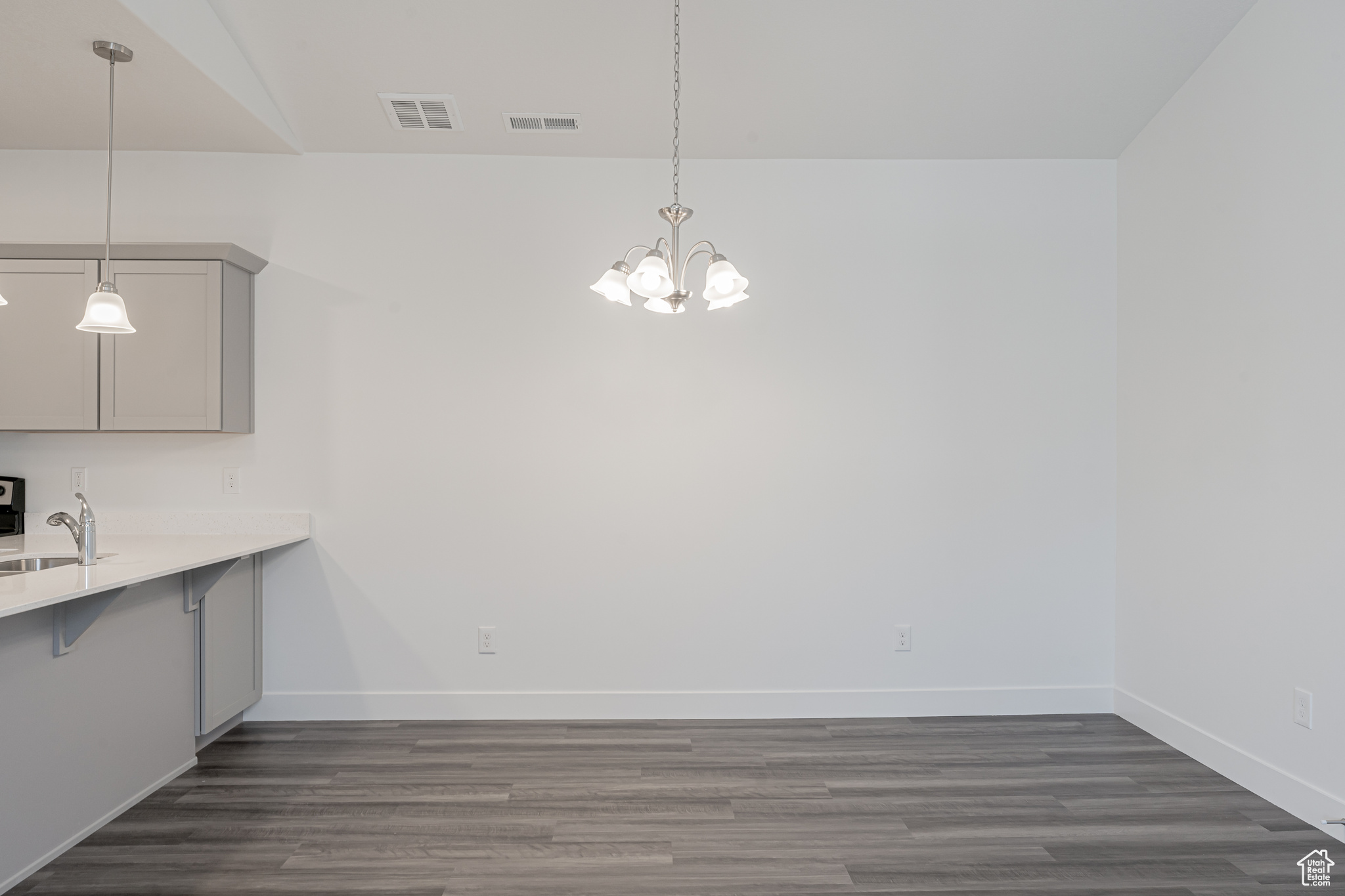 Unfurnished dining area with lofted ceiling, an inviting chandelier, sink, and dark hardwood / wood-style flooring