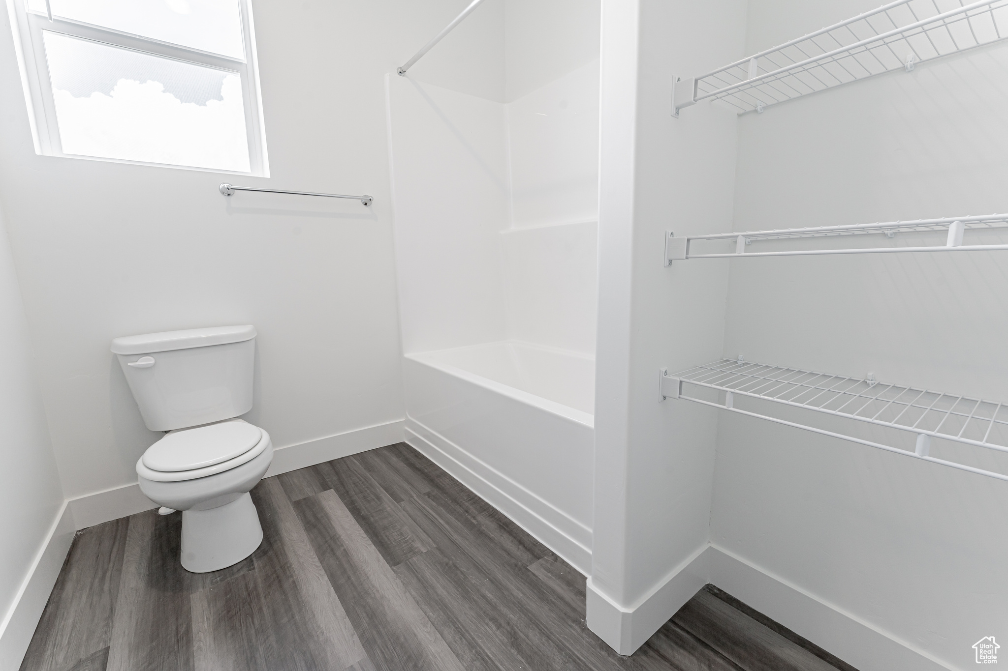 Bathroom with shower / tub combination, toilet, and hardwood / wood-style flooring