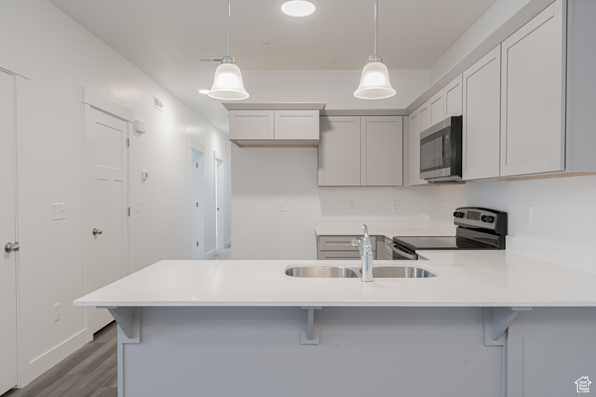 Kitchen featuring a kitchen bar, pendant lighting, kitchen peninsula, and appliances with stainless steel finishes