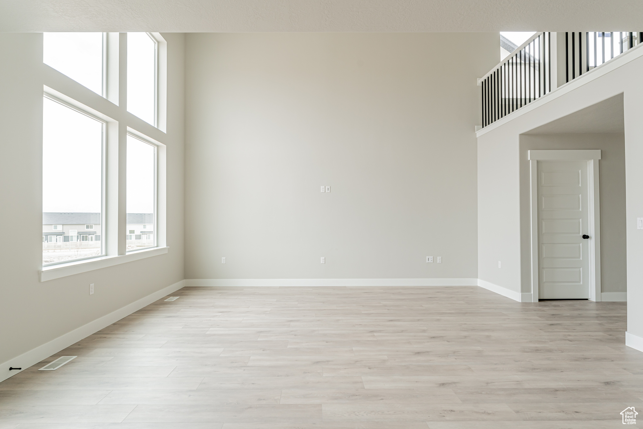 Spare room featuring a towering ceiling and light wood-type flooring