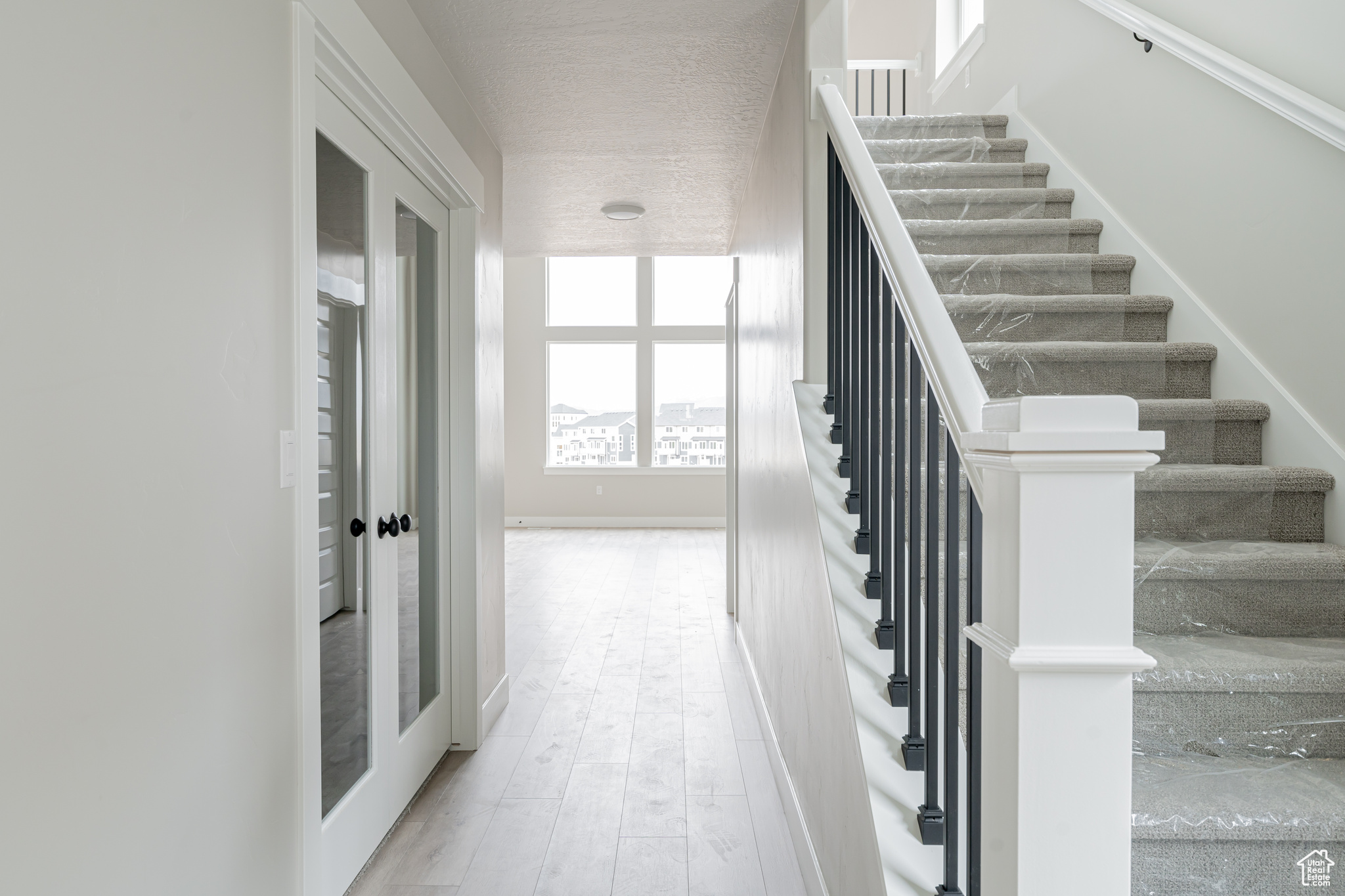 Stairs with a textured ceiling and light hardwood / wood-style flooring