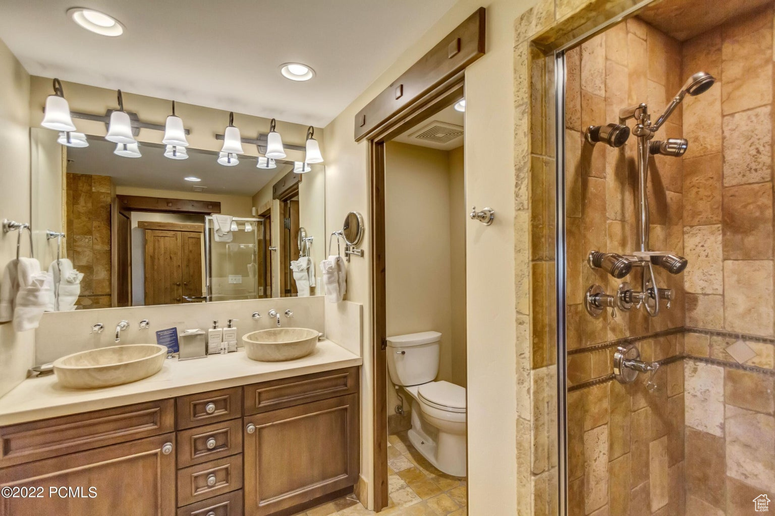 Bathroom with oversized vanity, walk in shower, double sink, toilet, and tile flooring