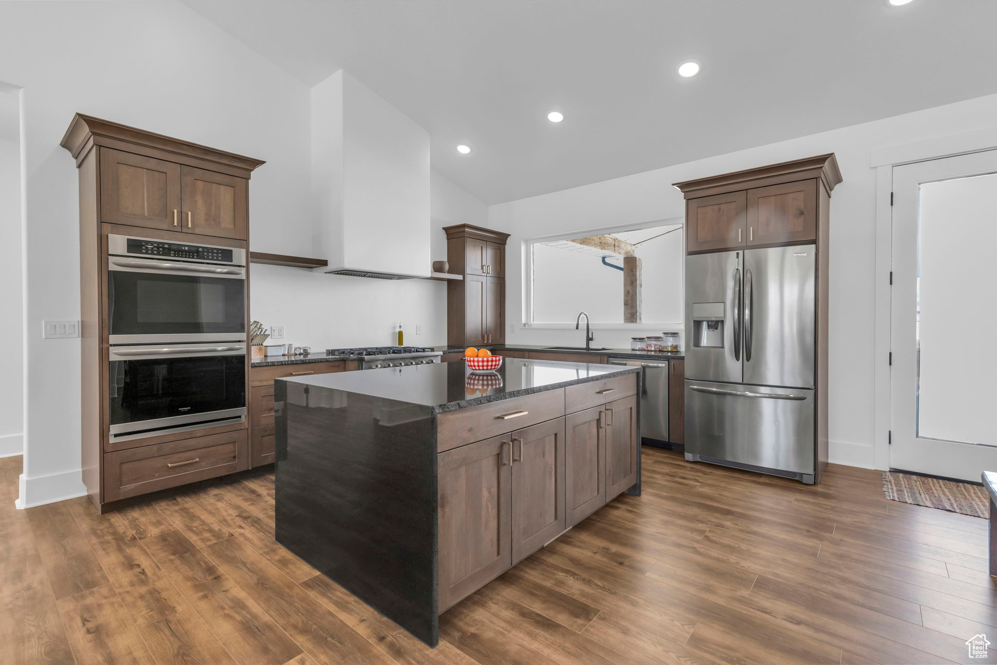Kitchen with dark stone counters, dark hardwood / wood-style flooring, a center island, and stainless steel appliances